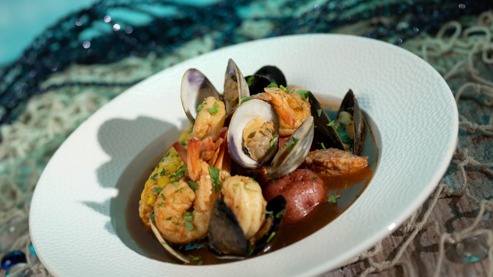 Un tazón de almejas al vapor, mejillones, camarones y salchicha Andouille con papas alargadas y maíz dulce en un caldo transparente