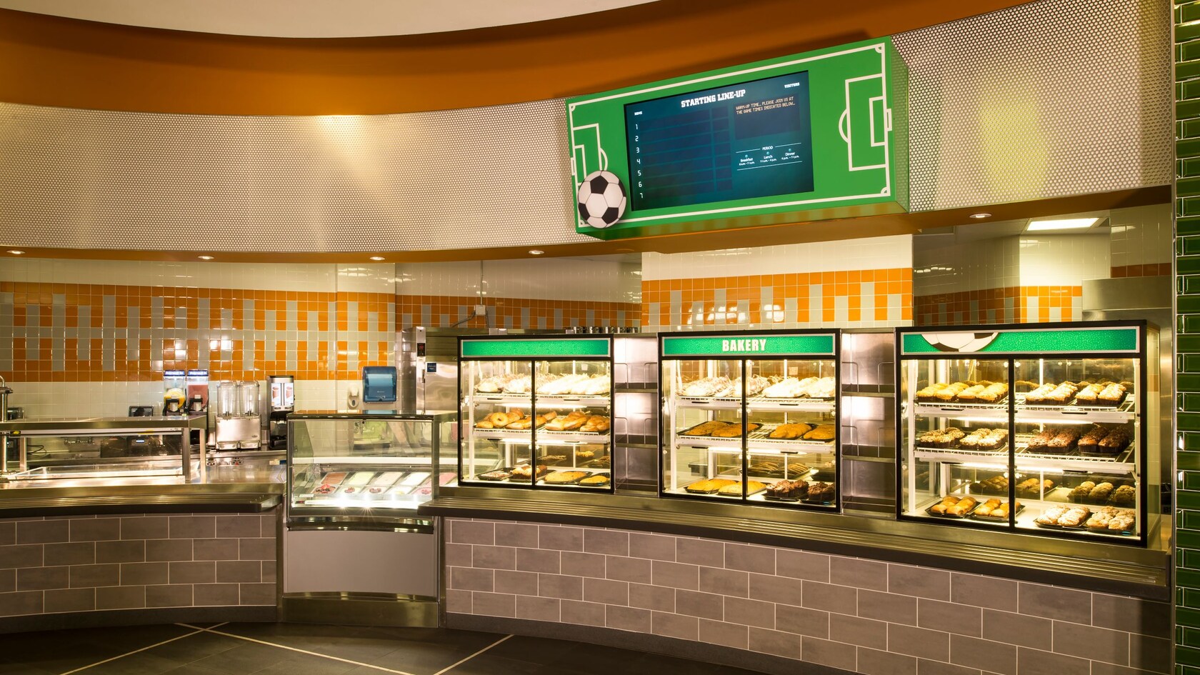A cafeteria area with desserts and pastries in a glass container under a sign that says ‘Bakery’