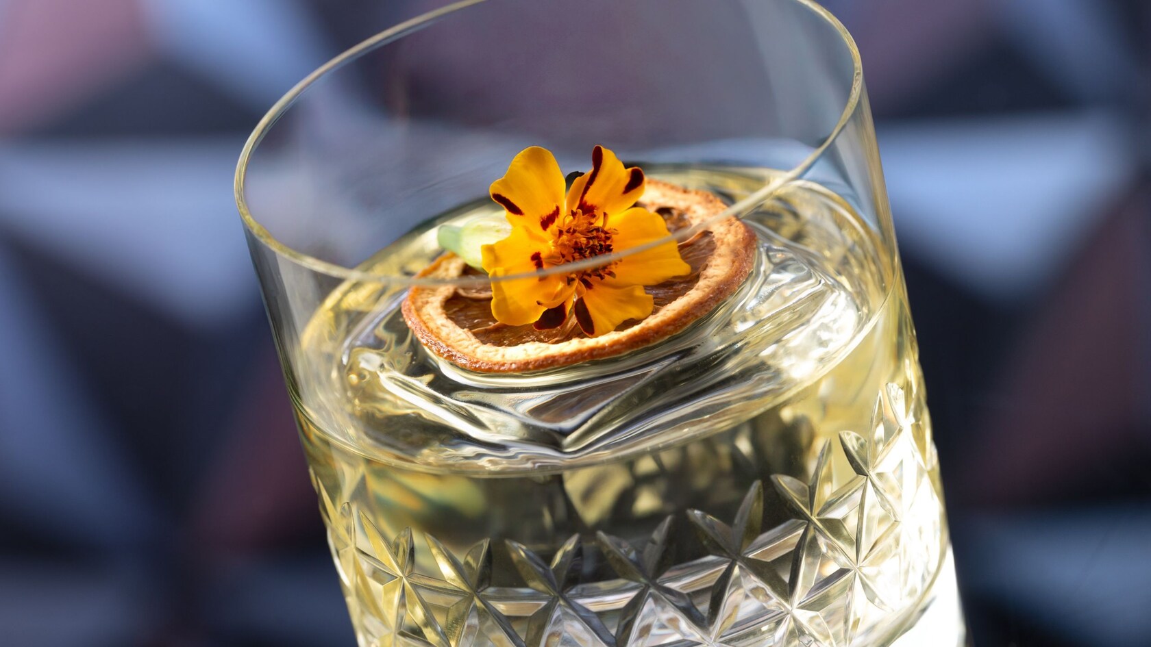 A cocktail topped with and orange slice and flower