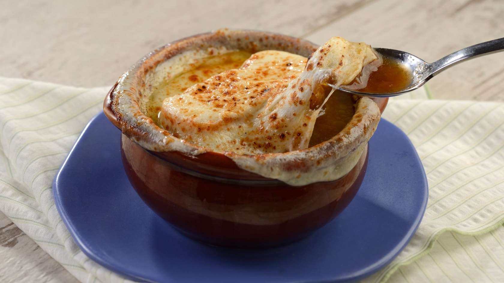 A spoon dipping into a bowl of French onion soup