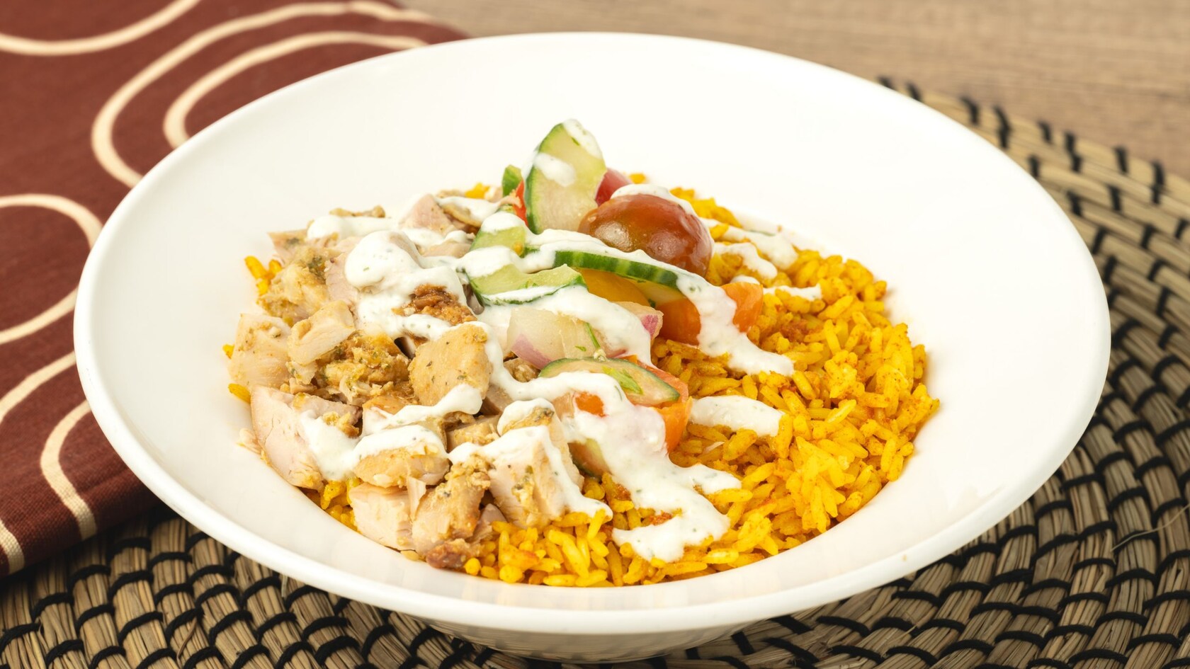 A Chicken Rice Bowl with chermoula-marinated chicken on jollof rice with kachumbari tomato salad and tzatziki sauce