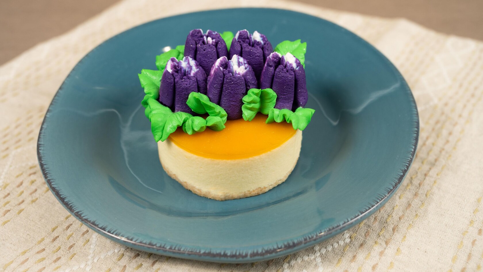 A portion of mango and passion fruit cheesecake topped with frosting flowers