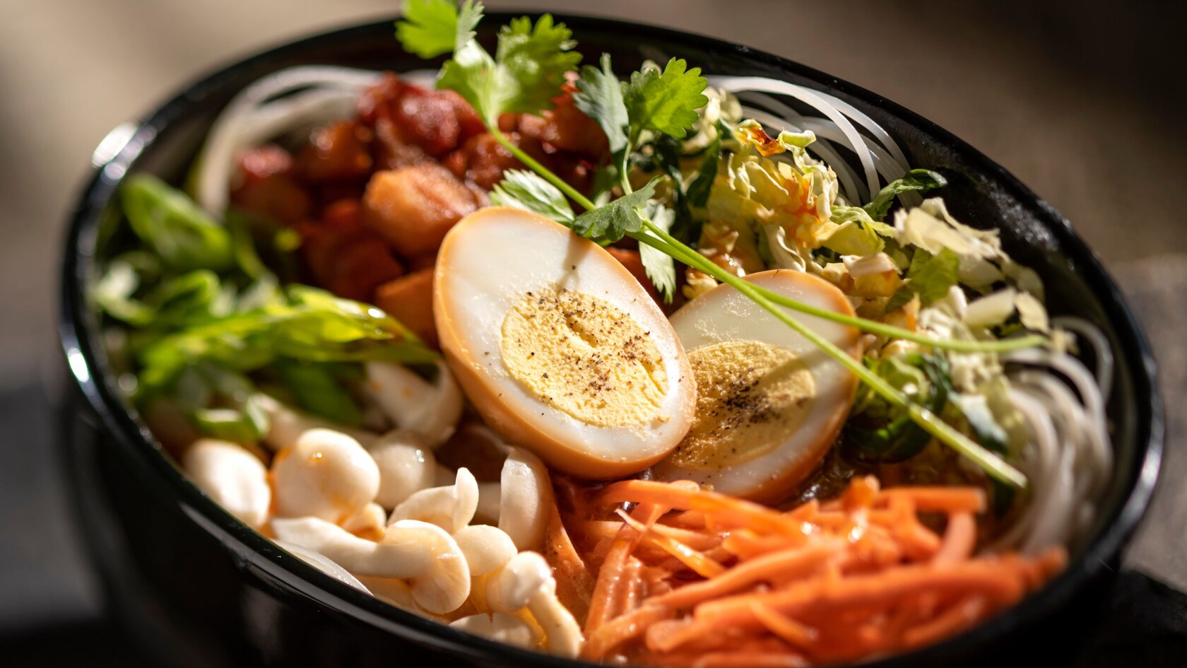 A bowl filled with meat and vegetables topped with hard boiled eggs 
