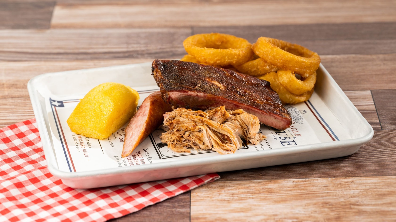 A B B Q Sampler with Memphis Dry-rubbed Pork Ribs, North Carolina Chopped Pork Butt, and Smoked Sausage with Cornbread and Onion Rings from Regal Eagle Smokehouse Craft Drafts and Barbecue