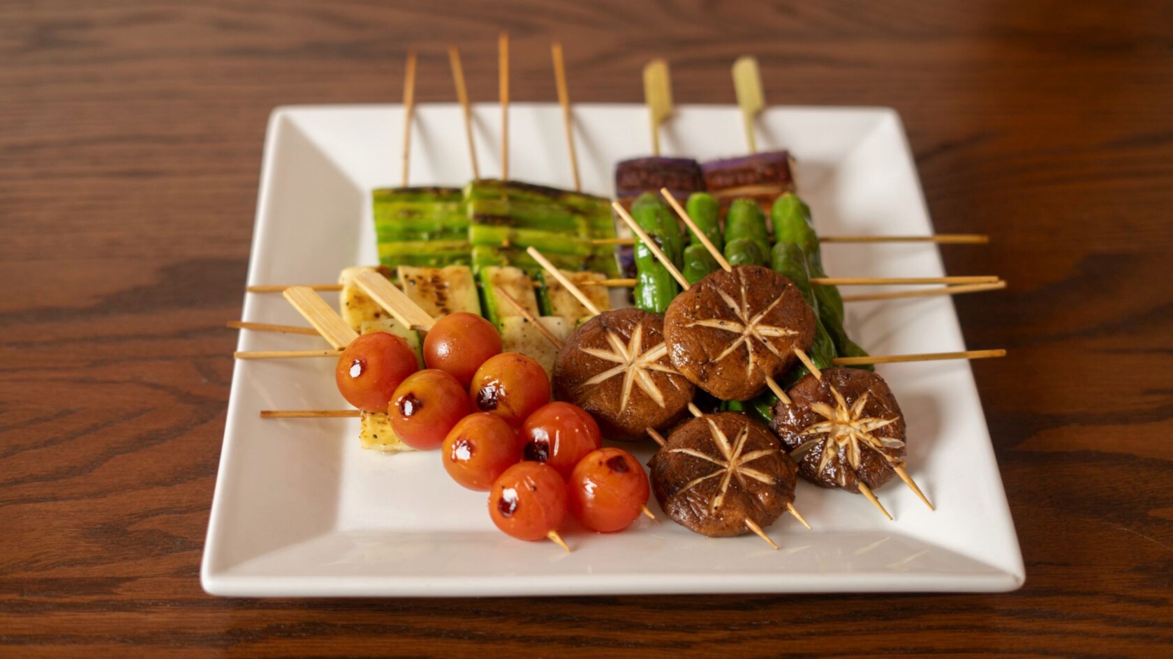 A plate of deep fried, skewered meats and vegetables