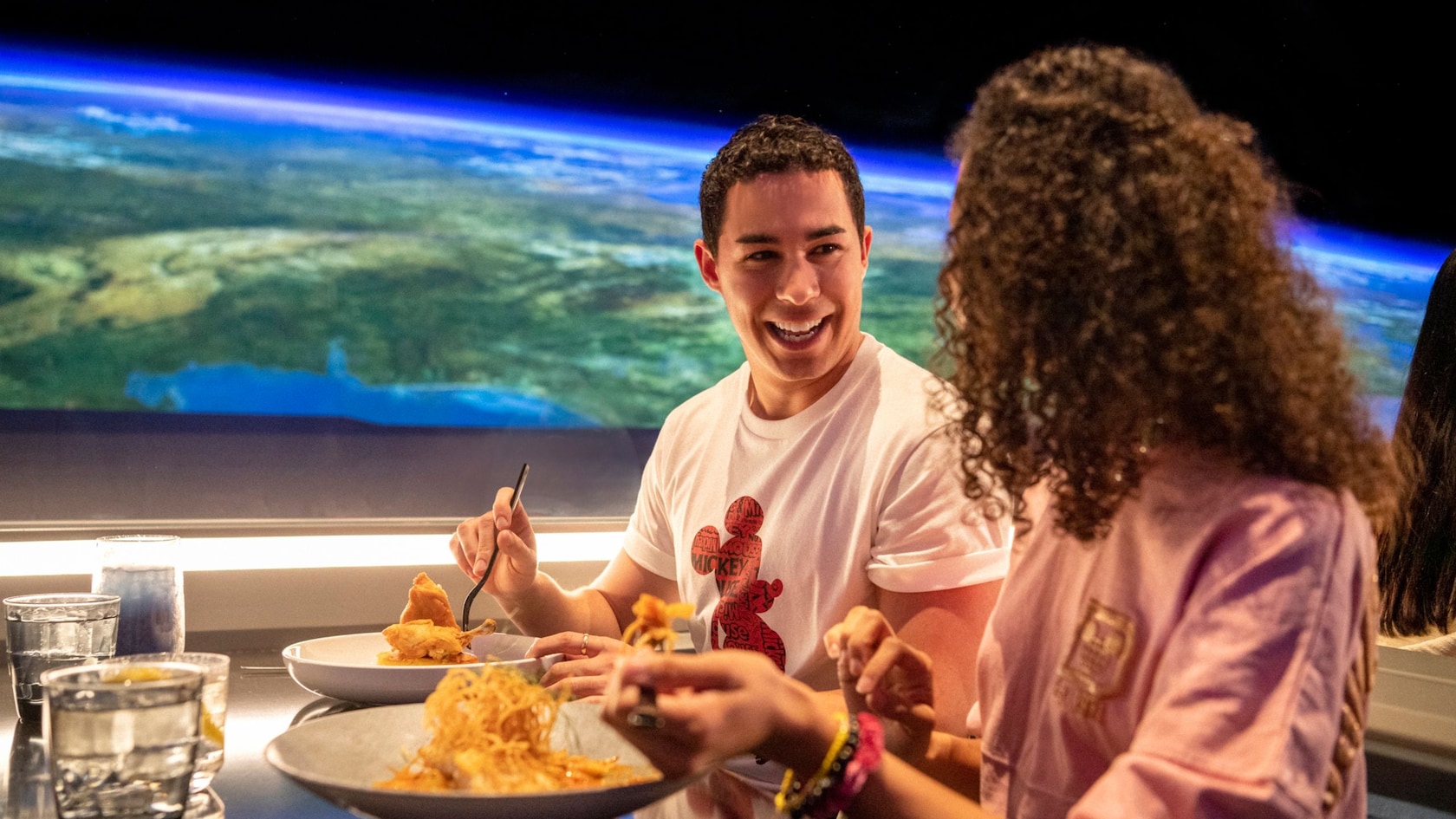 Una pareja disfruta de una deliciosa comida y bebidas especiales con la Tierra de fondo