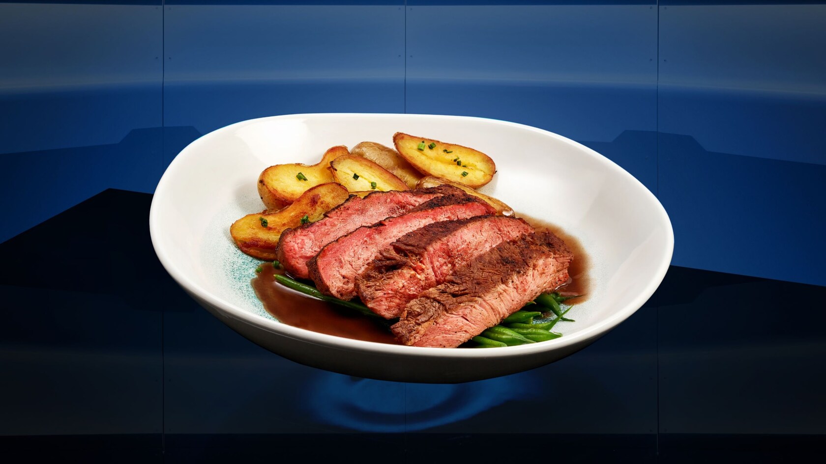 Bistec cortado en cuatro trozos y servido en un plato con un acompañante de papas