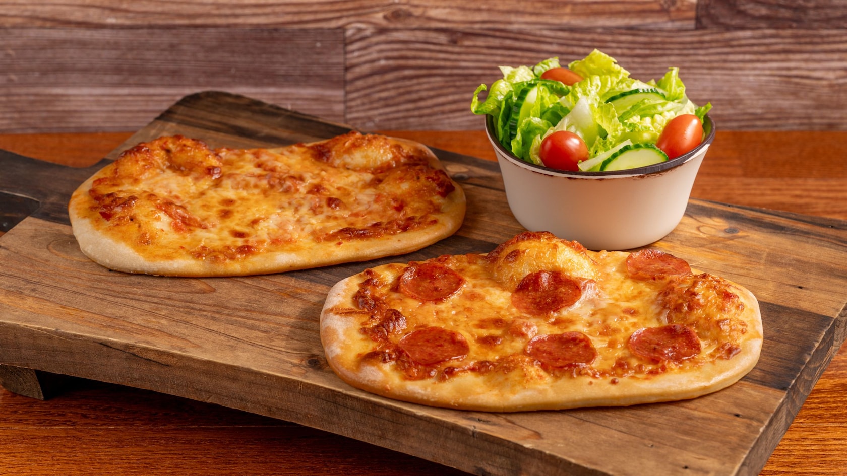 Una tabla de madera con dos panes planos de queso con una ensalada de acompañante de Sunshine Seasons en Epcot