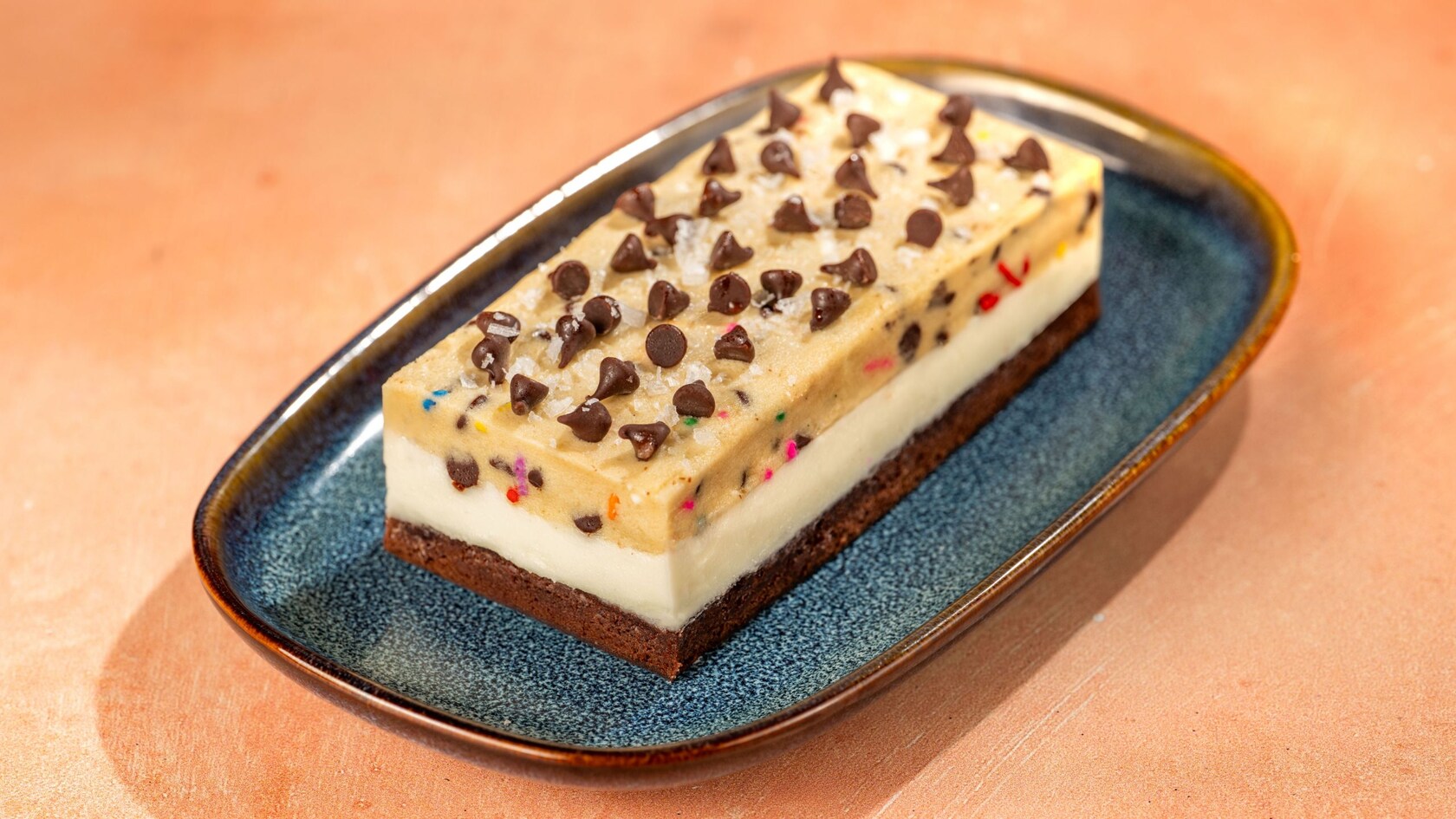 A layered cookie dough dessert bar on a plate