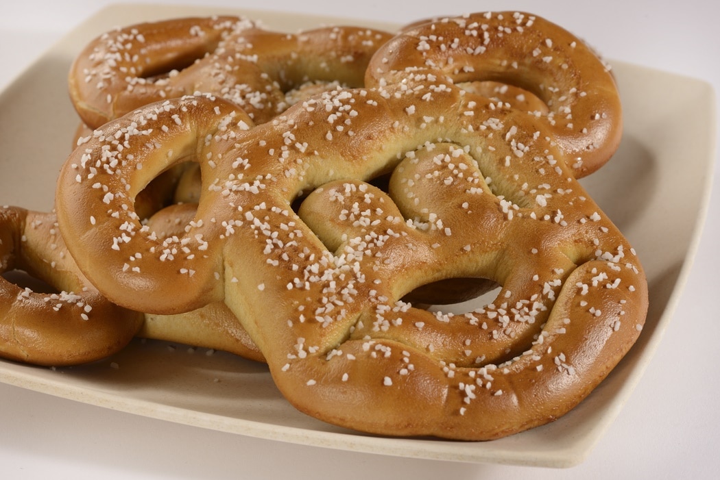 Soft pretzels in the shape of the head of Mickey Mouse, with salt sprinkled on them, on a plate