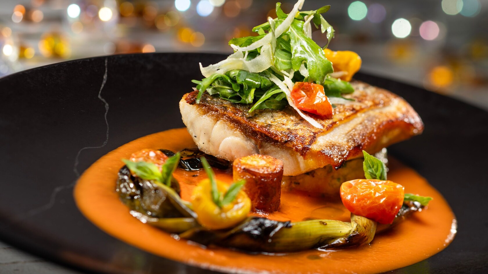 Lubina rayada de Topolino's Terrace, Flavors of the Riviera, con papas alargadas, aceitunas niçoise y coulis de tomate