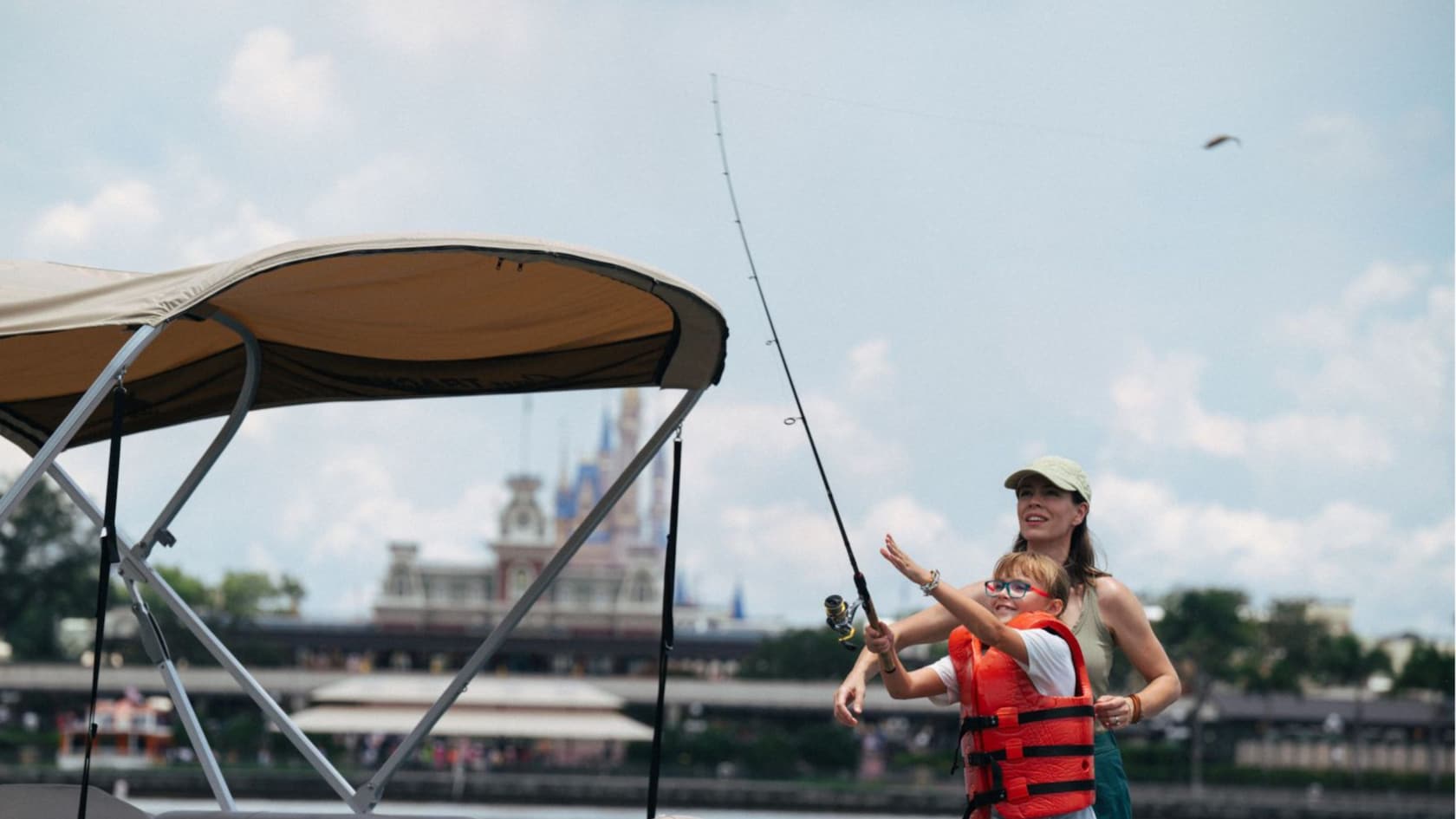 A mother observes as her daughter casts a line with a lure over the side of a boat