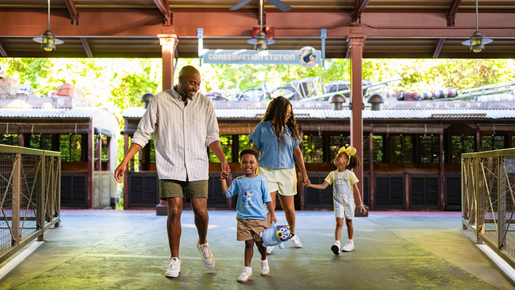 Family holding hands walking through the train station toward Conservation Station