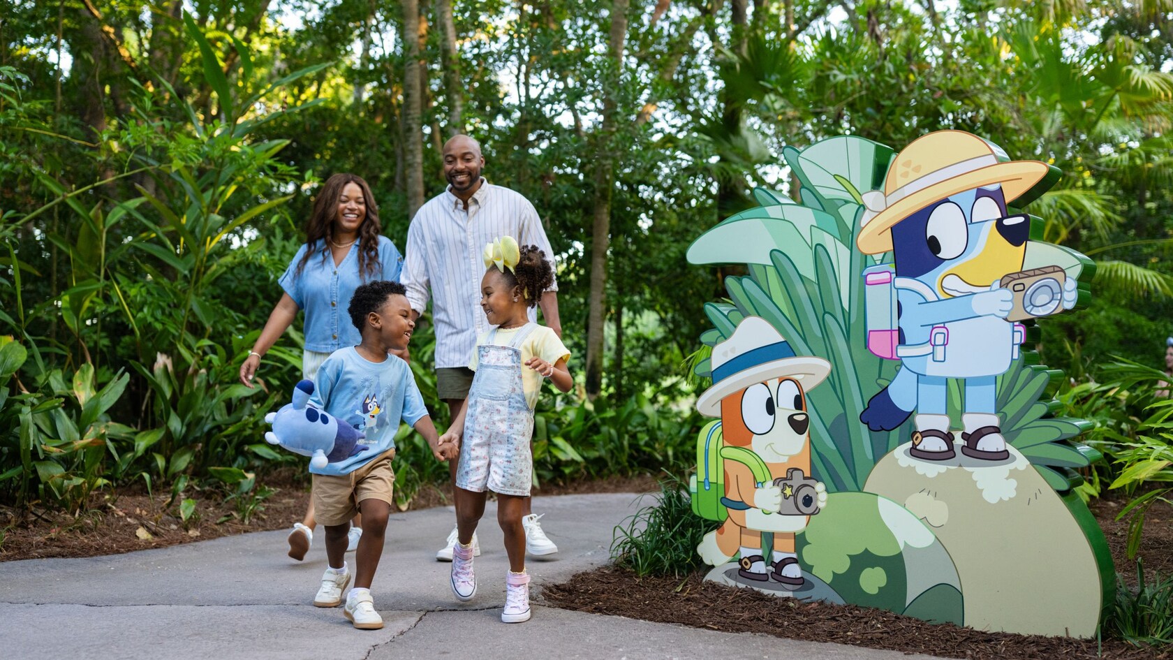 A family walking outside past signage showing Bingo and Bluey