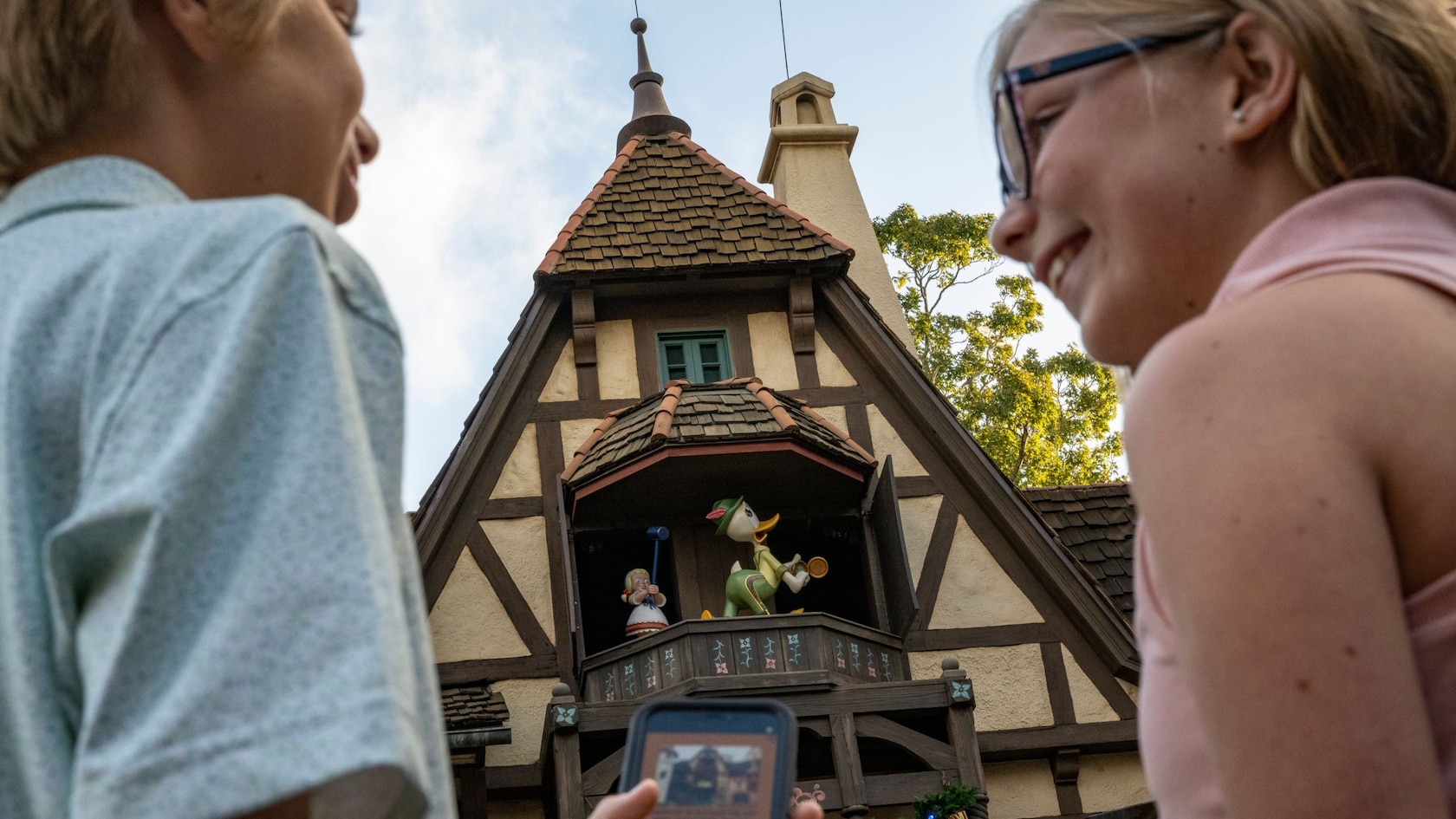 2 Guests hold a cellphone to make a Donald Duck figurine to appear during the DuckTales World Showcase Adventure