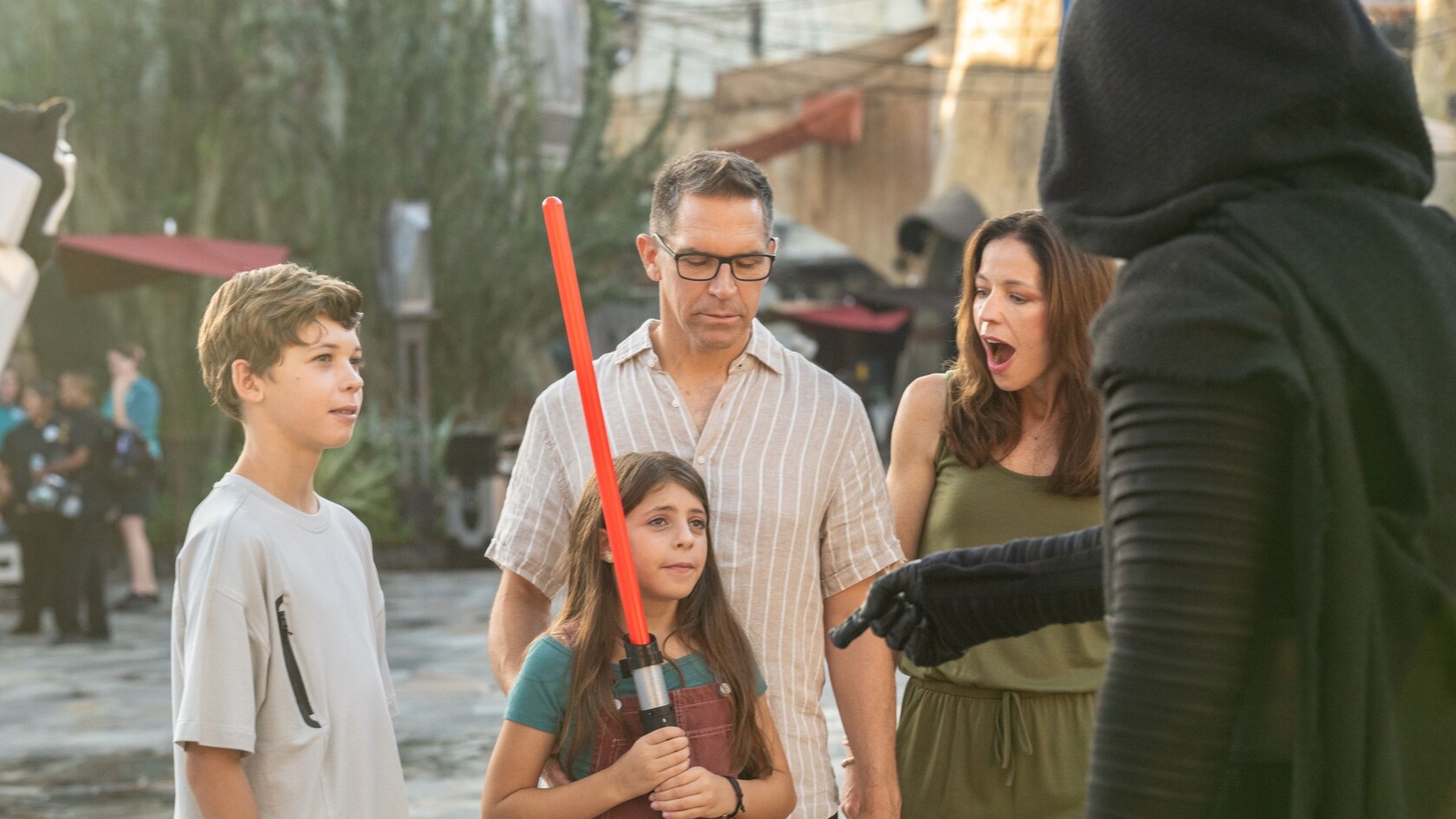 Kylo Ren meeting a young Guest holding a lightsaber and her family at Star Wars Galaxy’s Edge in Disney’s Hollywood Studios
