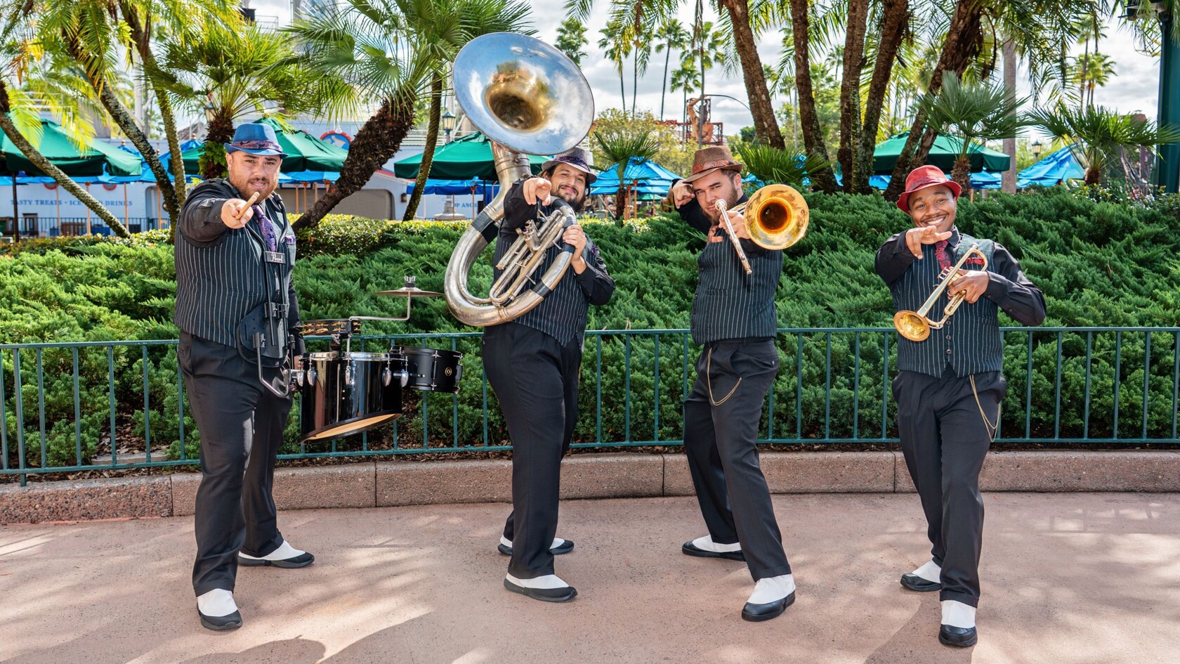 La banda HollyGroove Swinging posando con sus instrumentos delante de un exuberante fondo de vegetación en Disney's Hollywood Studios.