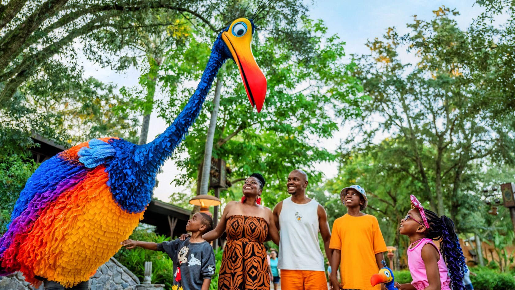 A family of 4 interacting with Kevin, a colorful larger-than-life bird