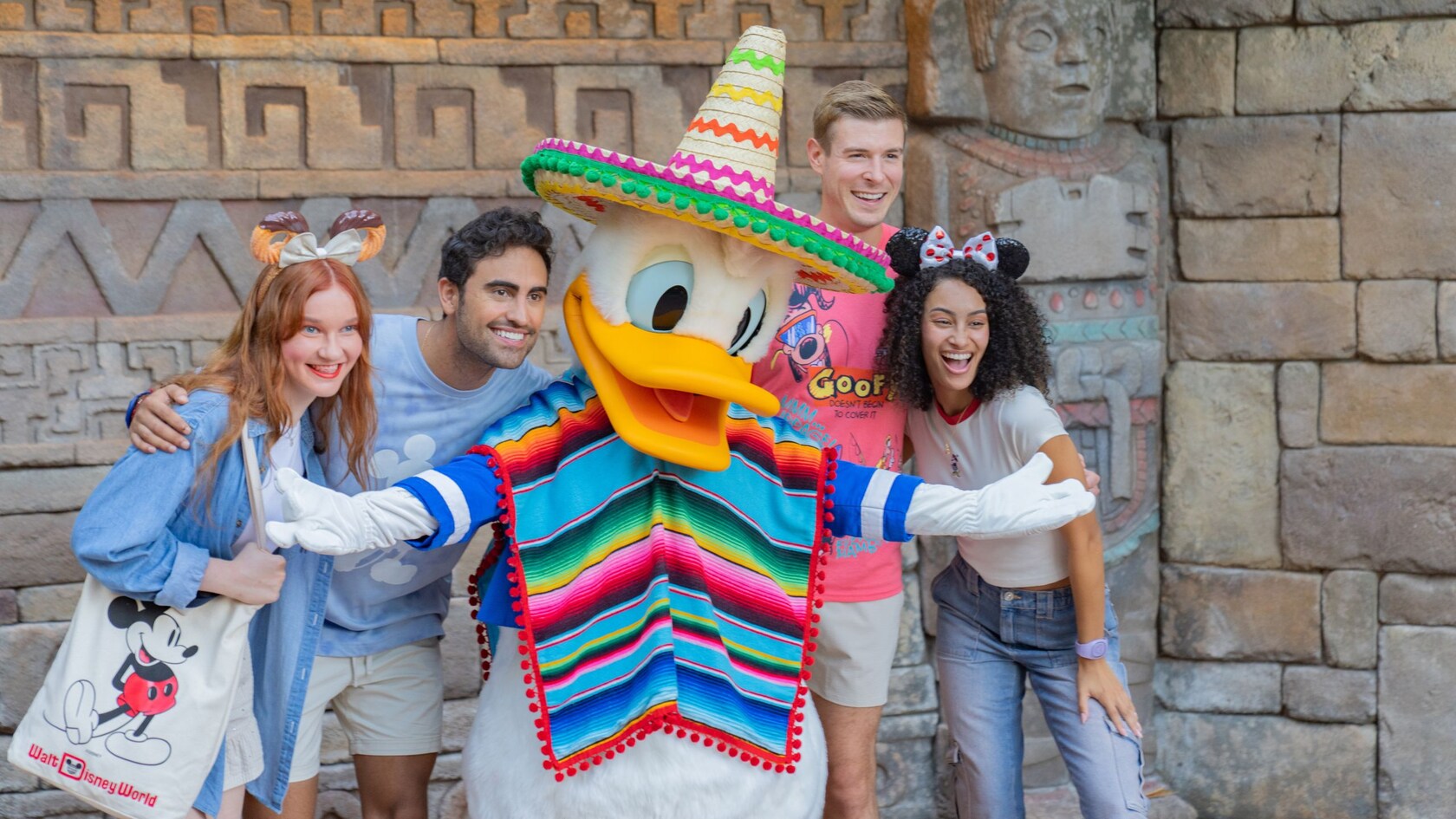 Four young adult Guests posing with Donald Duck wearing a poncho and sombrero