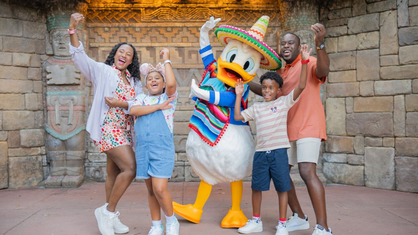 A family of 4 posing with Donald Duck wearing a poncho and sombrero
