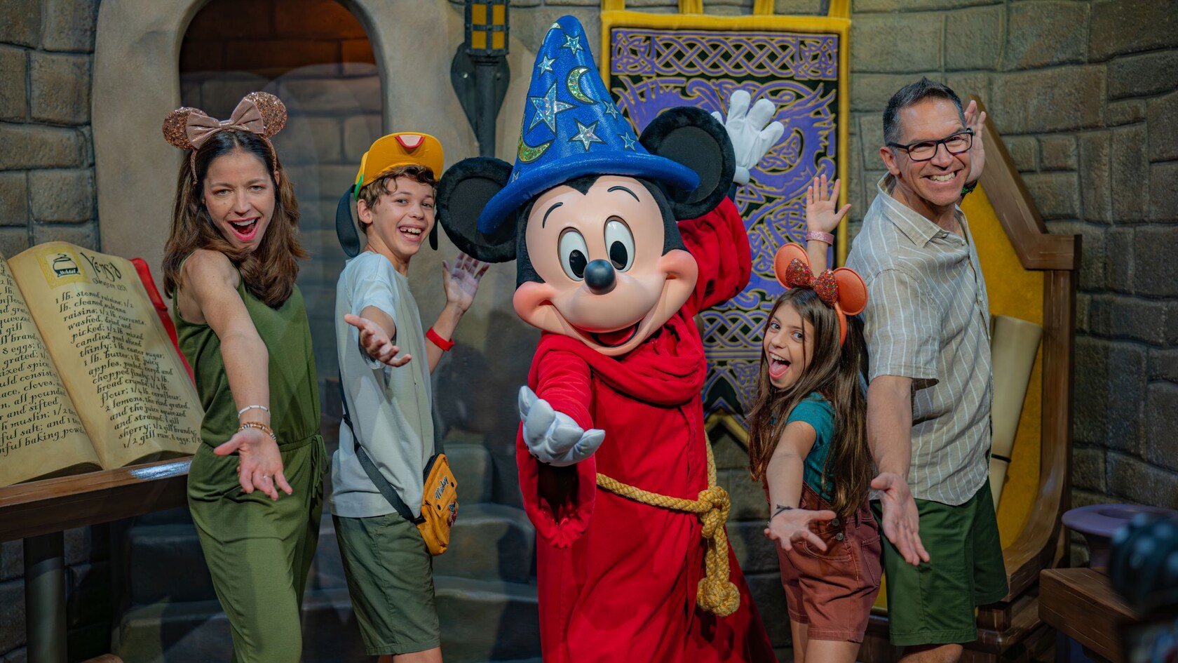A family of 4 posing for a photo with Sorcerer´s Apprentice Mickey Mouse in Meet Disney Stars at Red Carpet Dreams