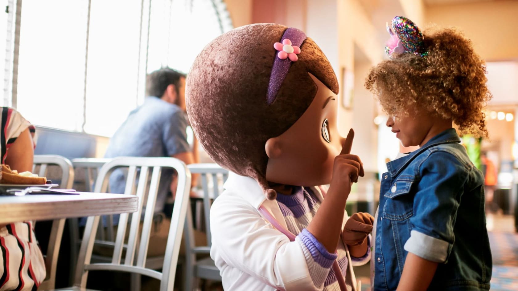 Una niña habla con Doc McStuffins frente a una mesa en el restaurante Hollywood & Vine