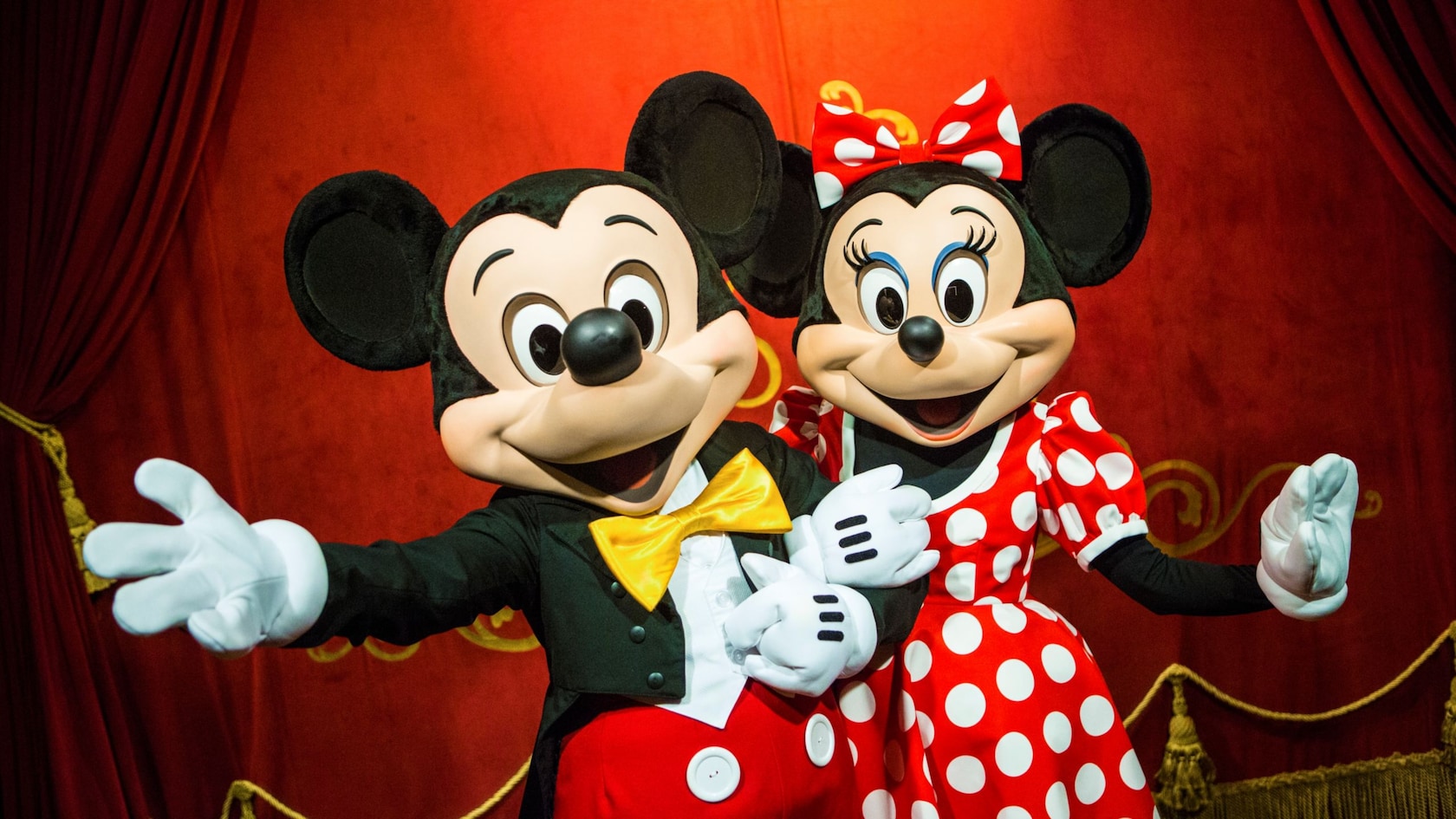 Mickey Mouse and Minnie Mouse link arms and pose for a picture
