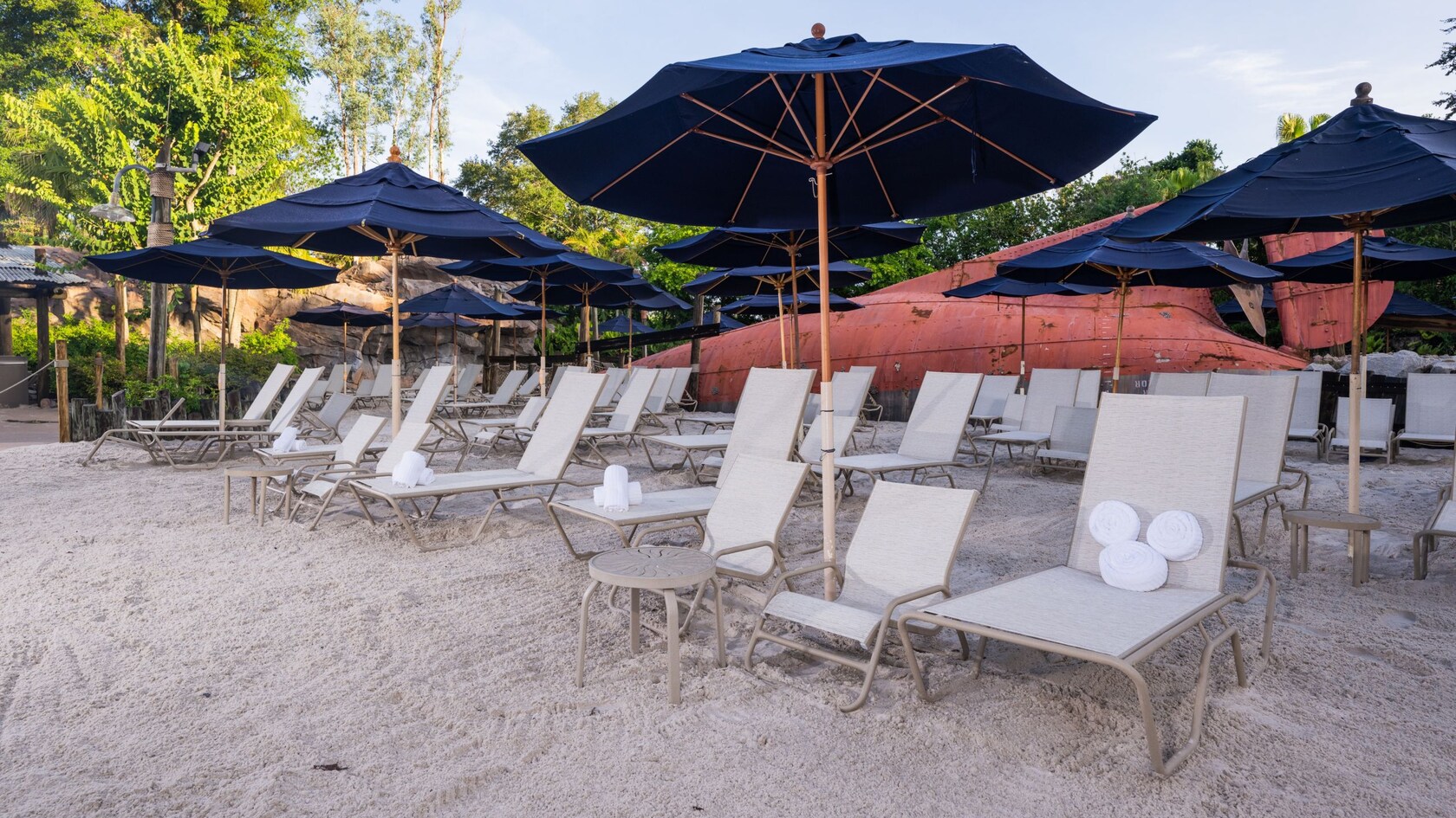 Rows of lounge chairs with rolled towels beneath umbrellas on a beach at Disney's Typhoon Lagoon