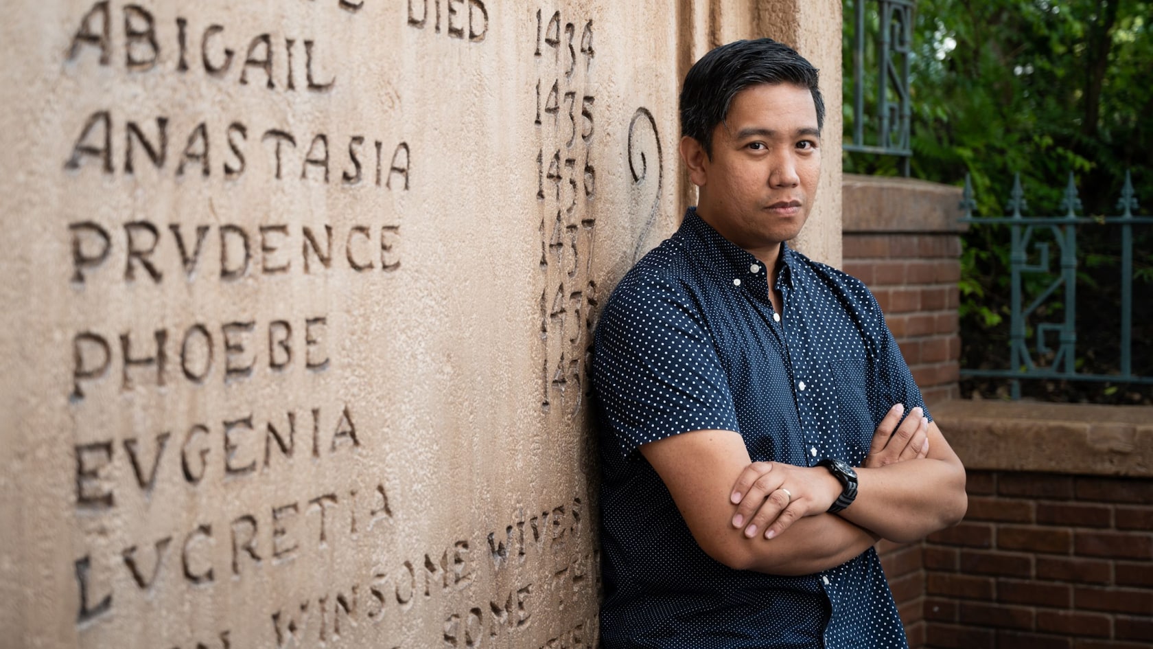 A man stands in front of a stone carving near the Haunted Mansion