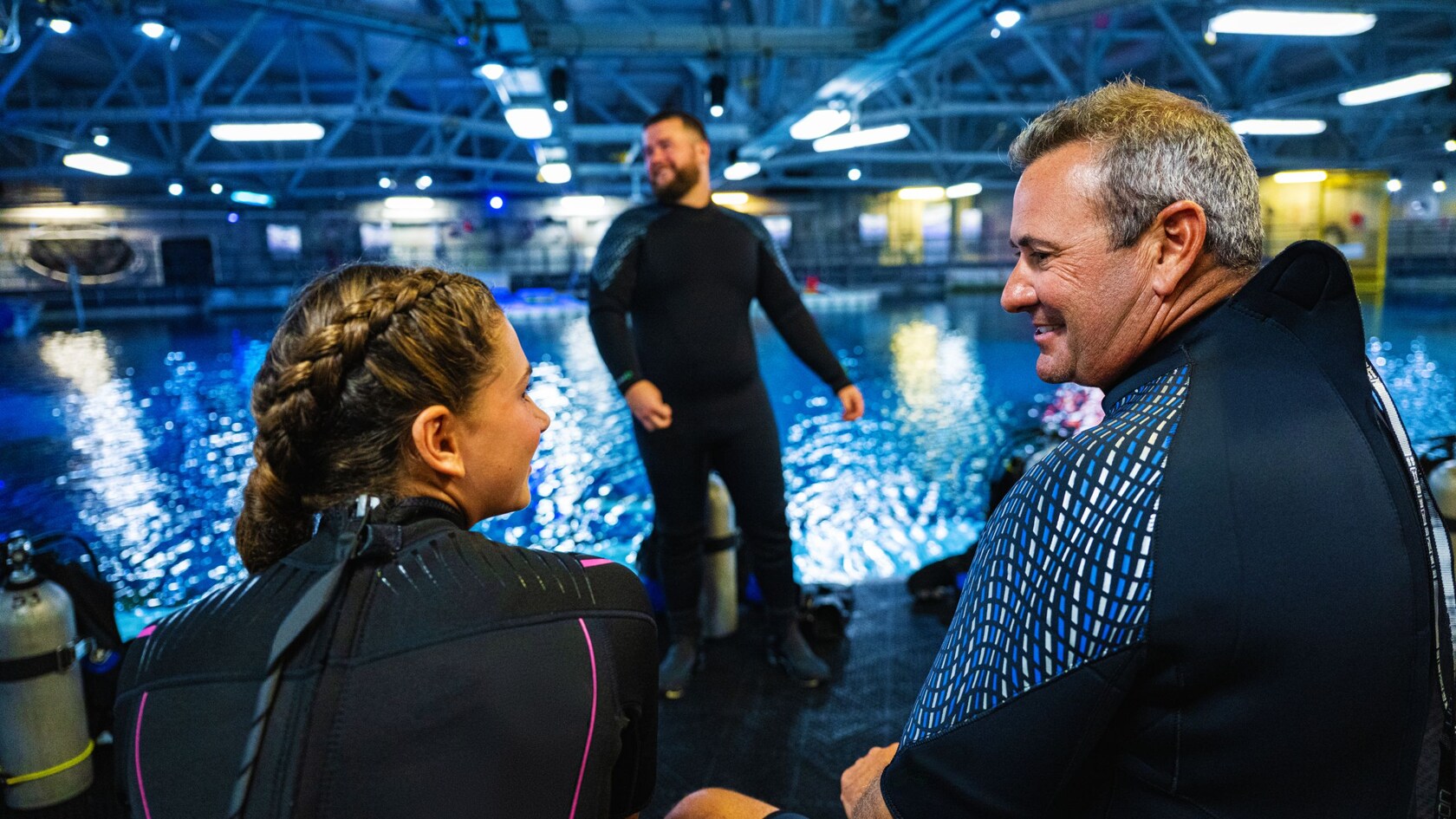 A teenage girl and her father, both in wetsuits at the Epcot DiveQuest facility  