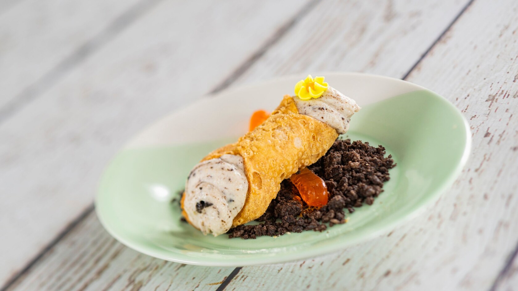 A Chocolate Dirt Cannoli with a gummy worm and chocolate crumbs