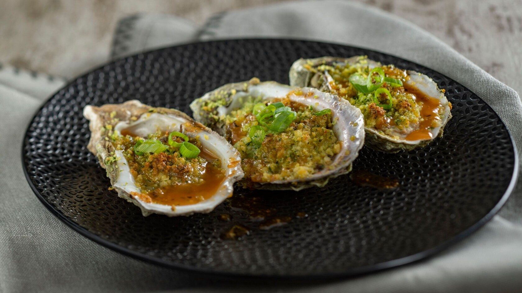 A plate with 3 Cajun Style Roasted Oysters from Magnolia Terrace