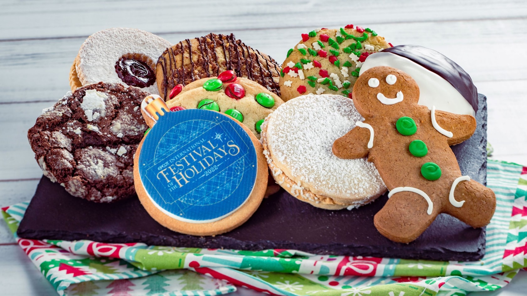 An assortment of holiday themed cookies, including a gingerbread man and one in the shape of a Christmas tree ornament