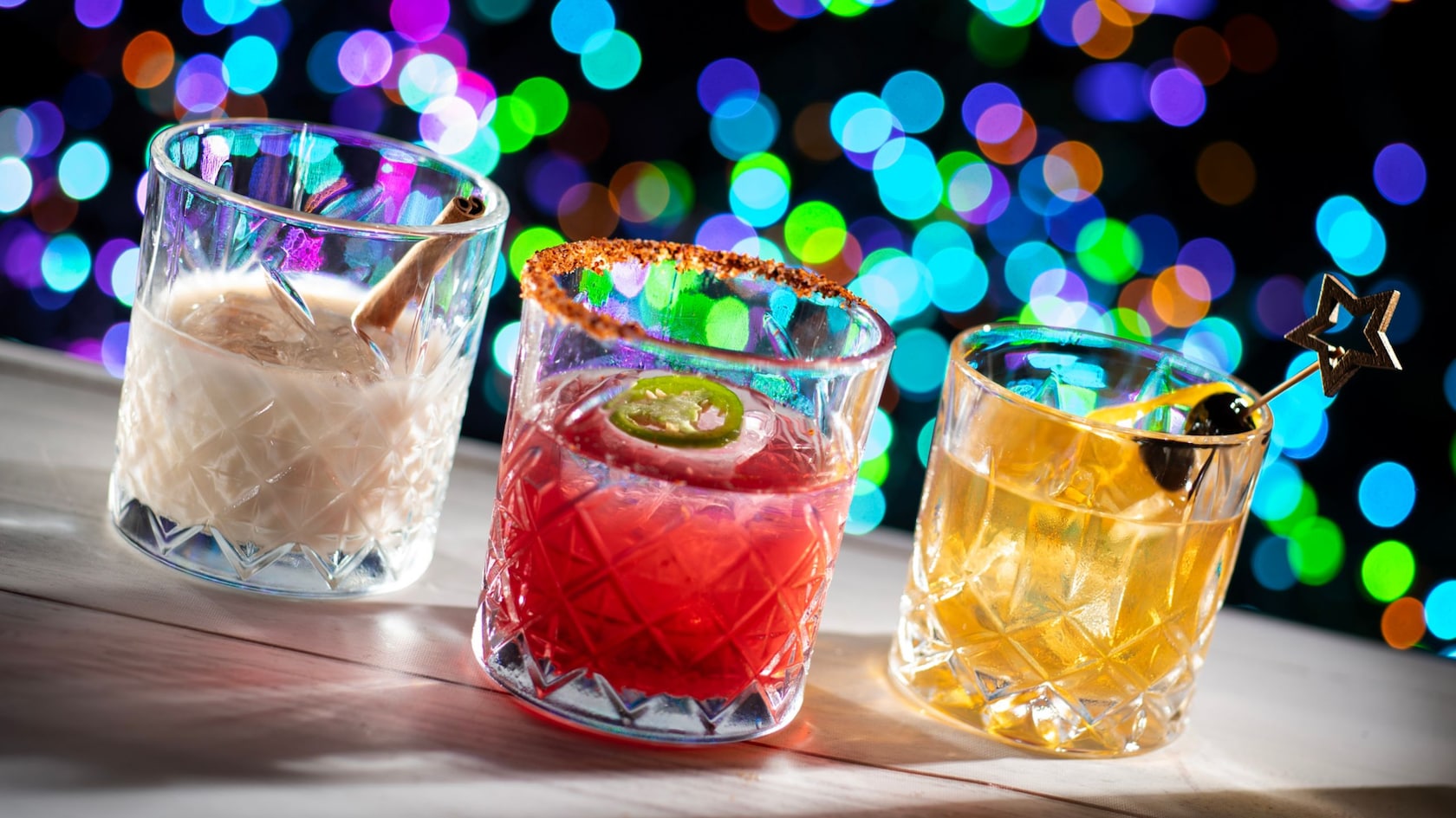 Three festive cocktails with cinnamon, jalapeño and cherry garnishes