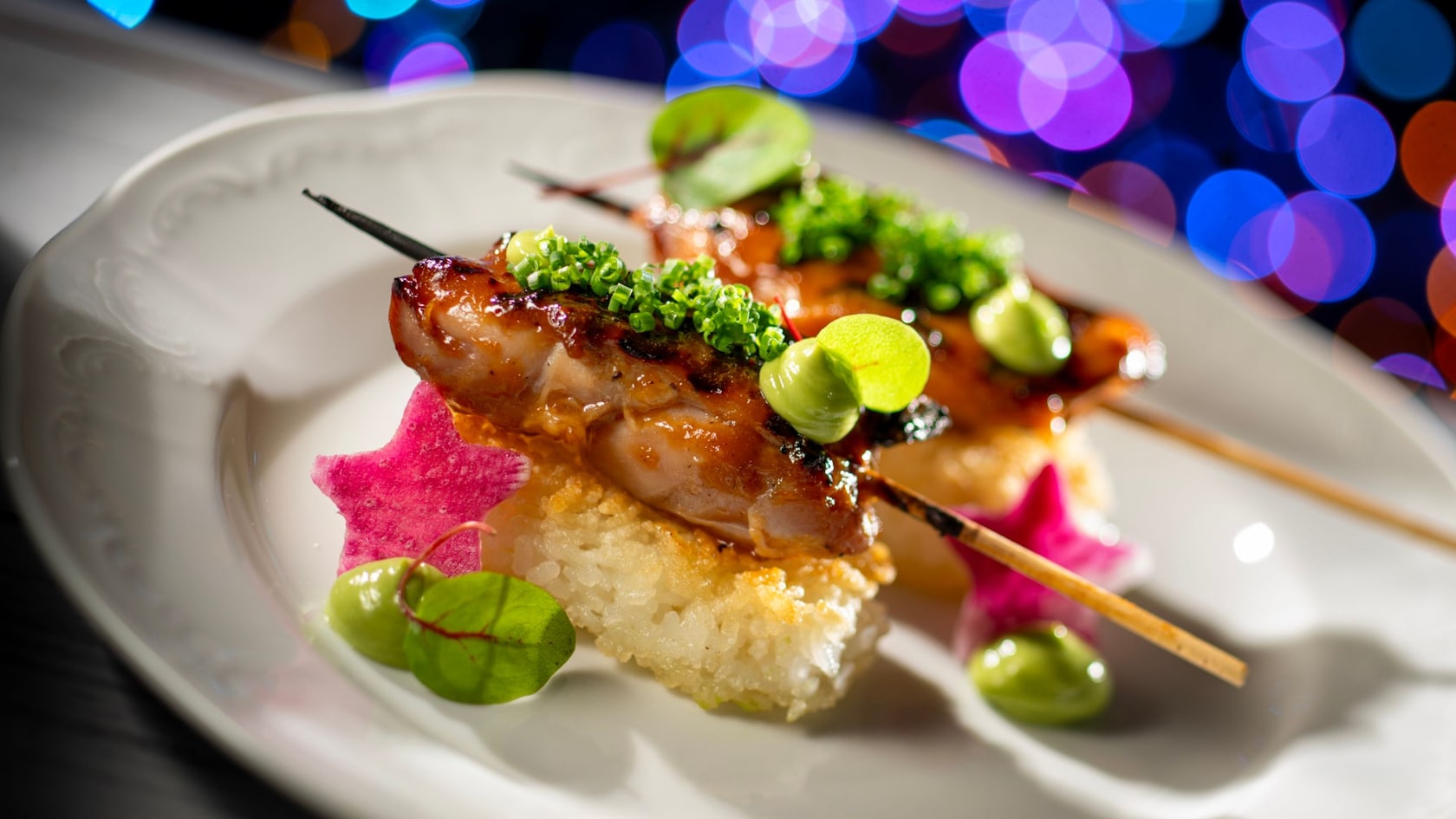 Two chicken yakitori skewers topped with green onion, served over crispy rice