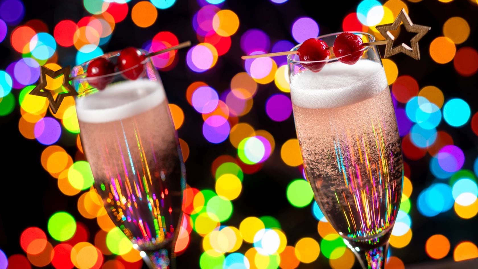 Two sparkling Poinsettia Fizz champagne cocktails garnished with cherries and star picks