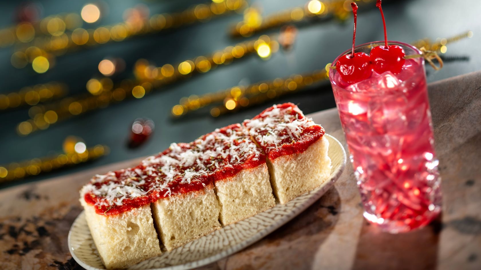 Sliced tomato pie topped with cheese beside a cherry lemonade from Hurly Burly at Disney’s Boardwalk