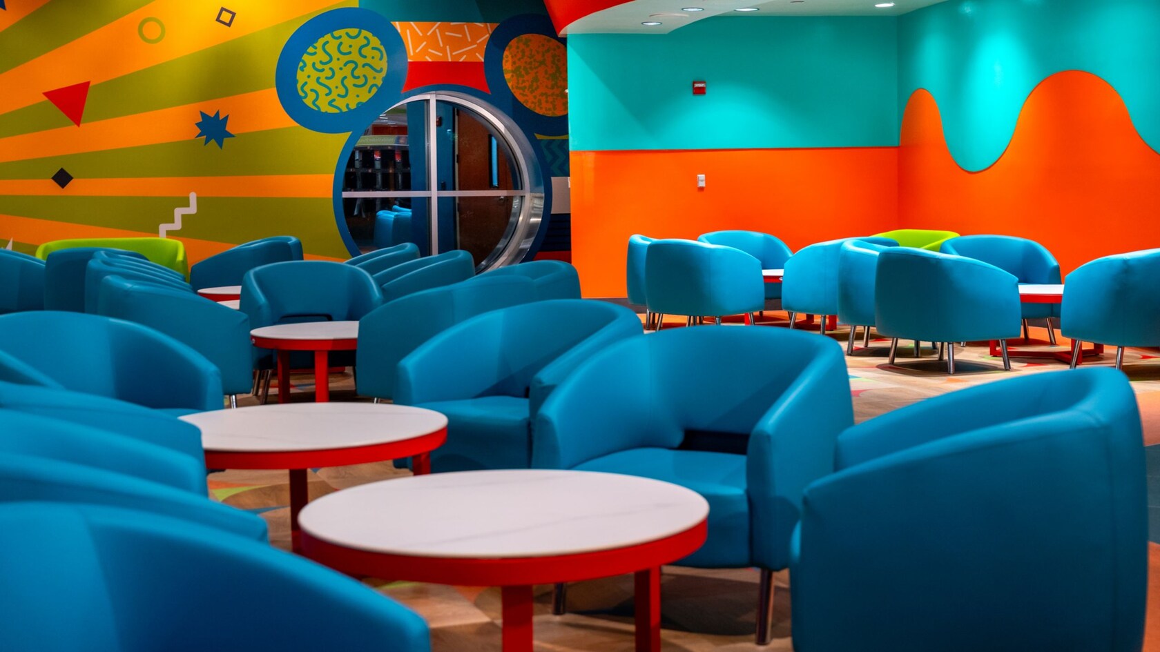 Padded chairs around low tables at Everything Pop Shopping & Dining in Disney’s Pop Century Resort	
