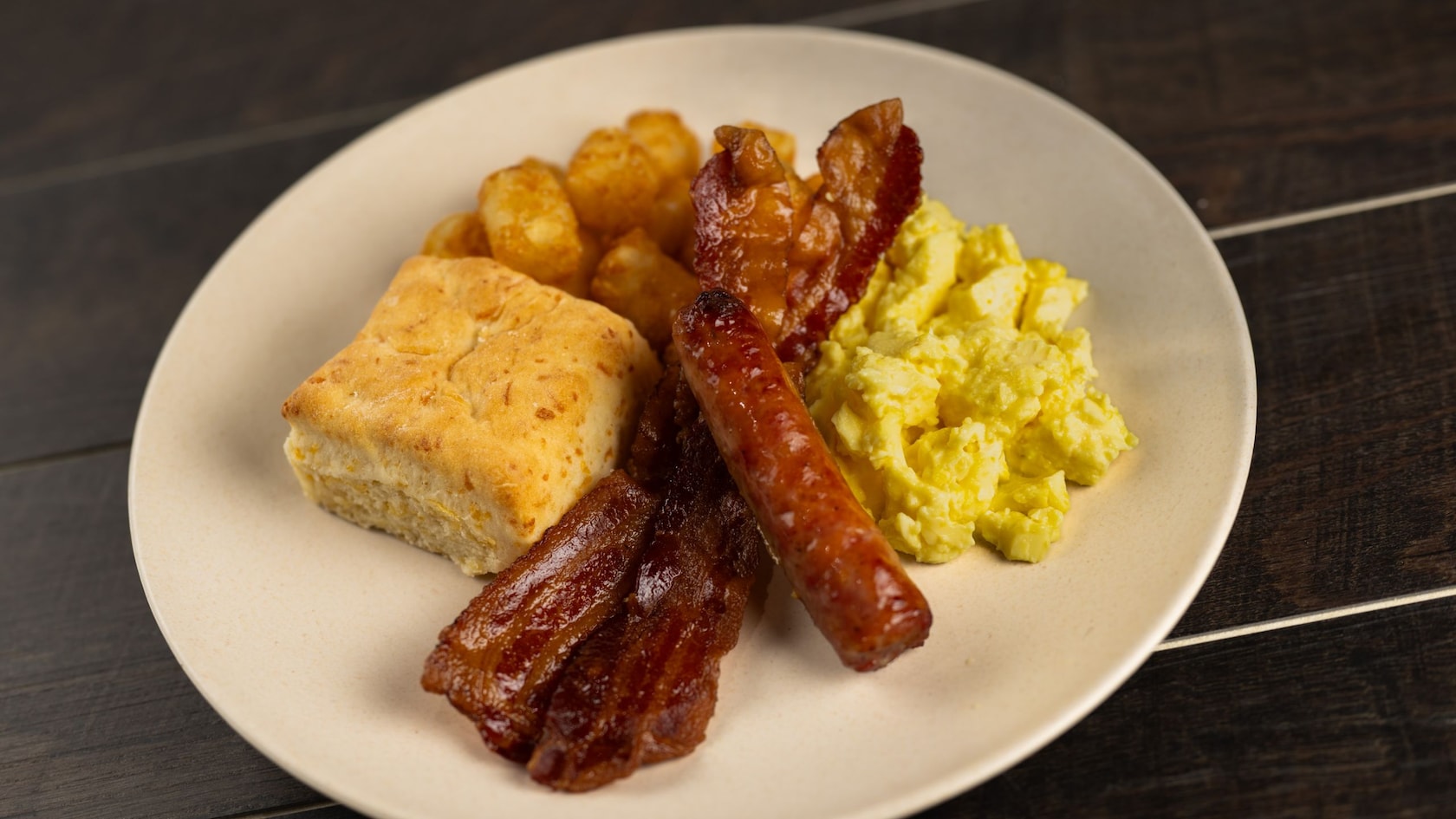 Uma travessa de café da manhã com ovos, linguiça, bacon, batatas e um pão biscuit de queijo do Roaring Fork no Disney’s Wilderness Lodge