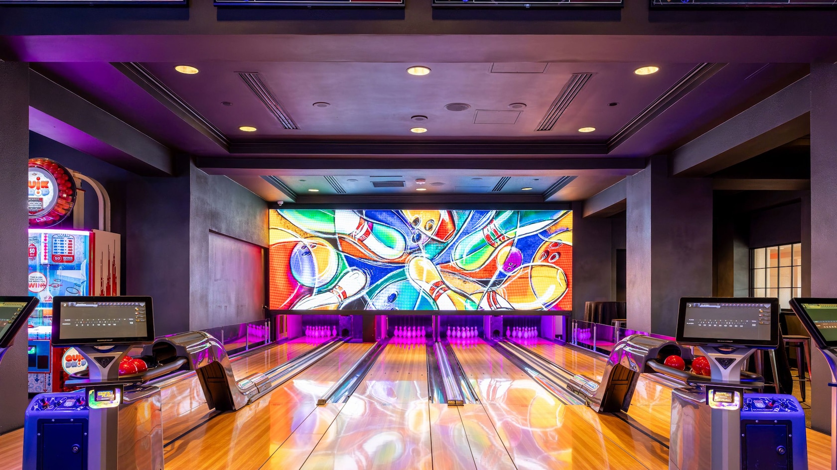 Cinco pistas de juego de bolos en Lagoon: Games, Lanes & Eats con marcadores digitales y una amplia pantalla en el fondo