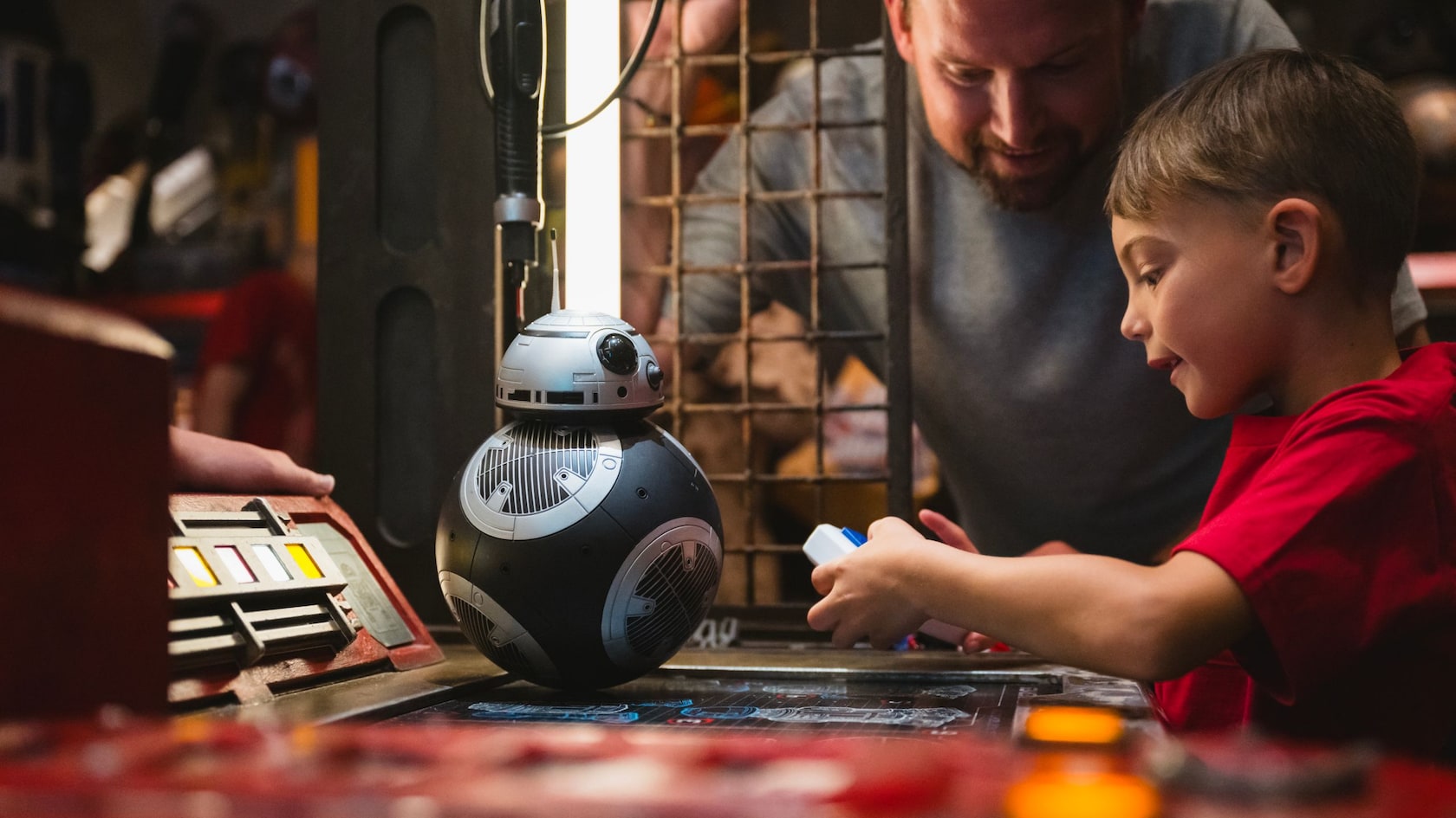 A father and son building a BB Series astromech droid on a workbench at the Droid Depot