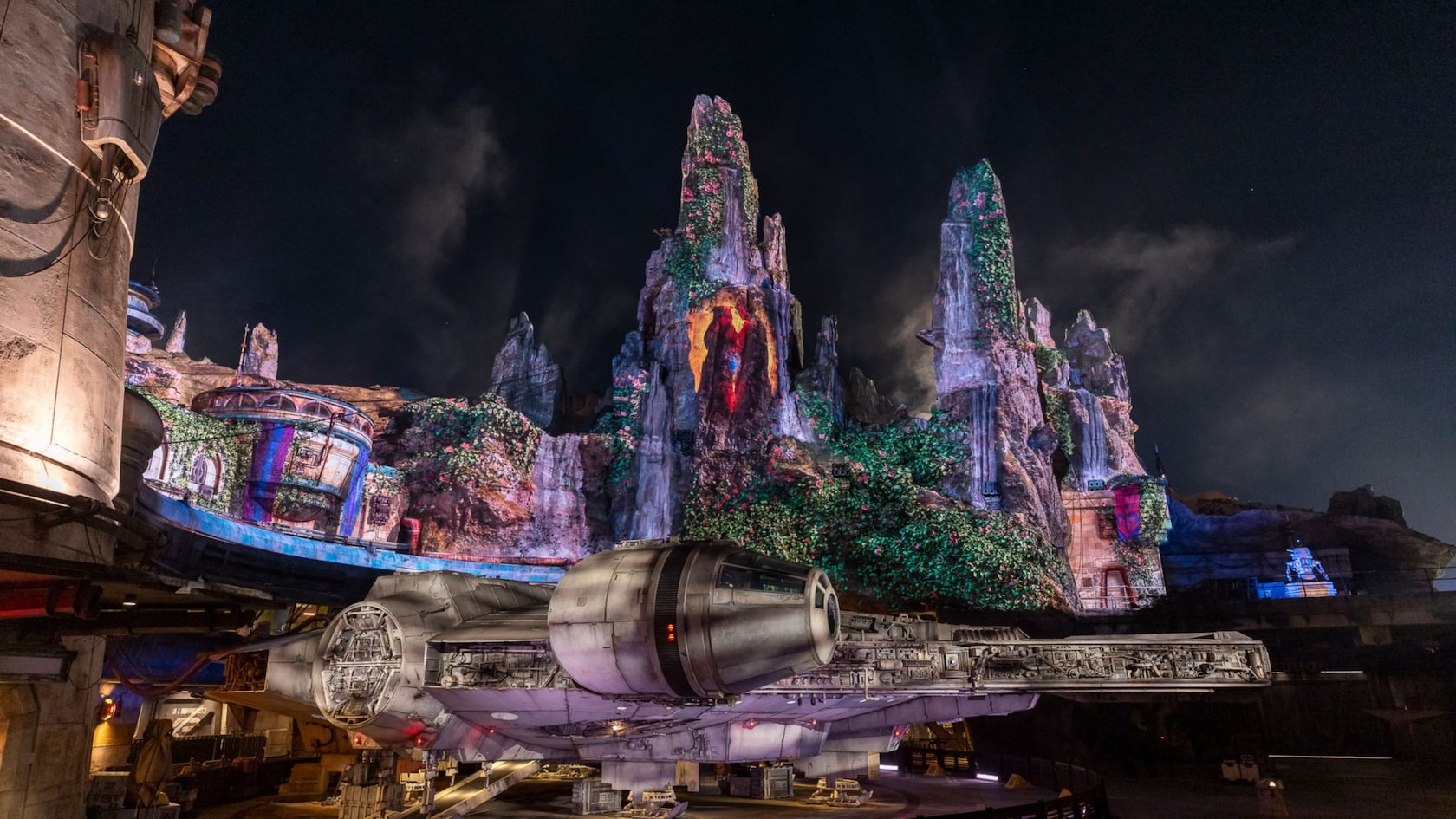 The Millennium Falcon in front of the spires of Batuu in Star Wars Galaxy's Edge at the Disneyland Resort at nighttime