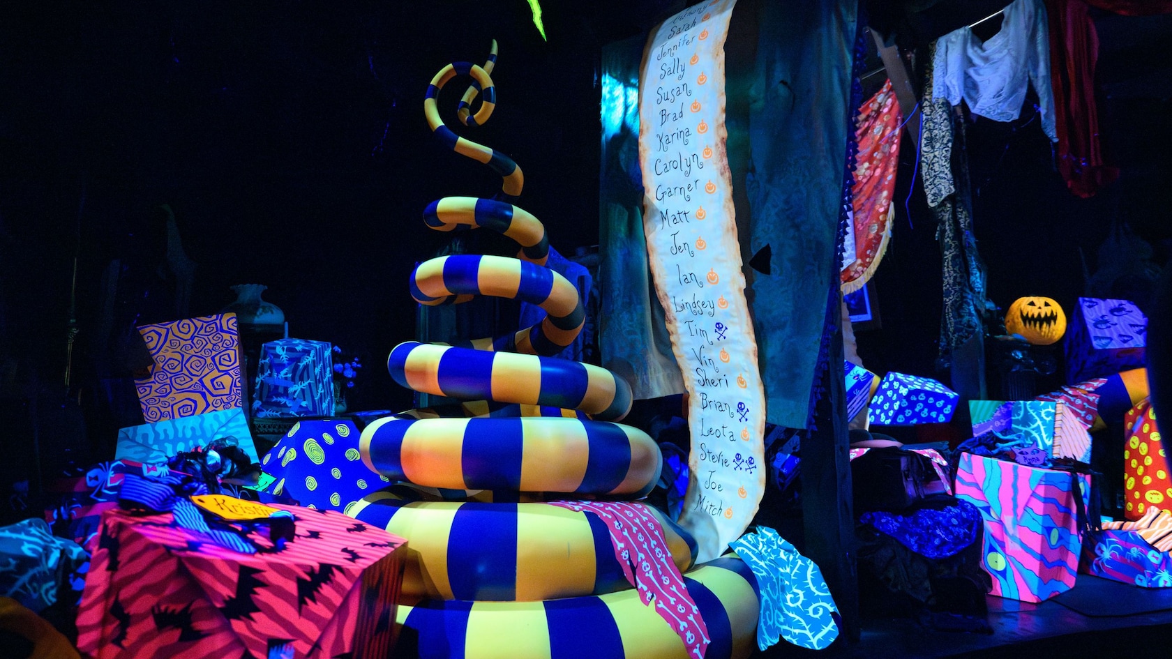 A snake coiled next to wrapped gifts and a naughty and nice list at Haunted Mansion Holiday