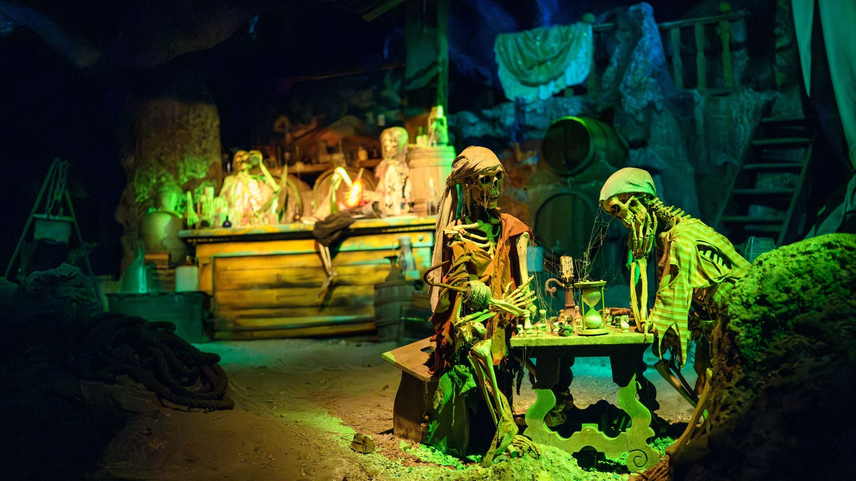 Dos esqueletos jugando ajedrez mientras otros dos beben en un bar en Pirates of the Caribbean