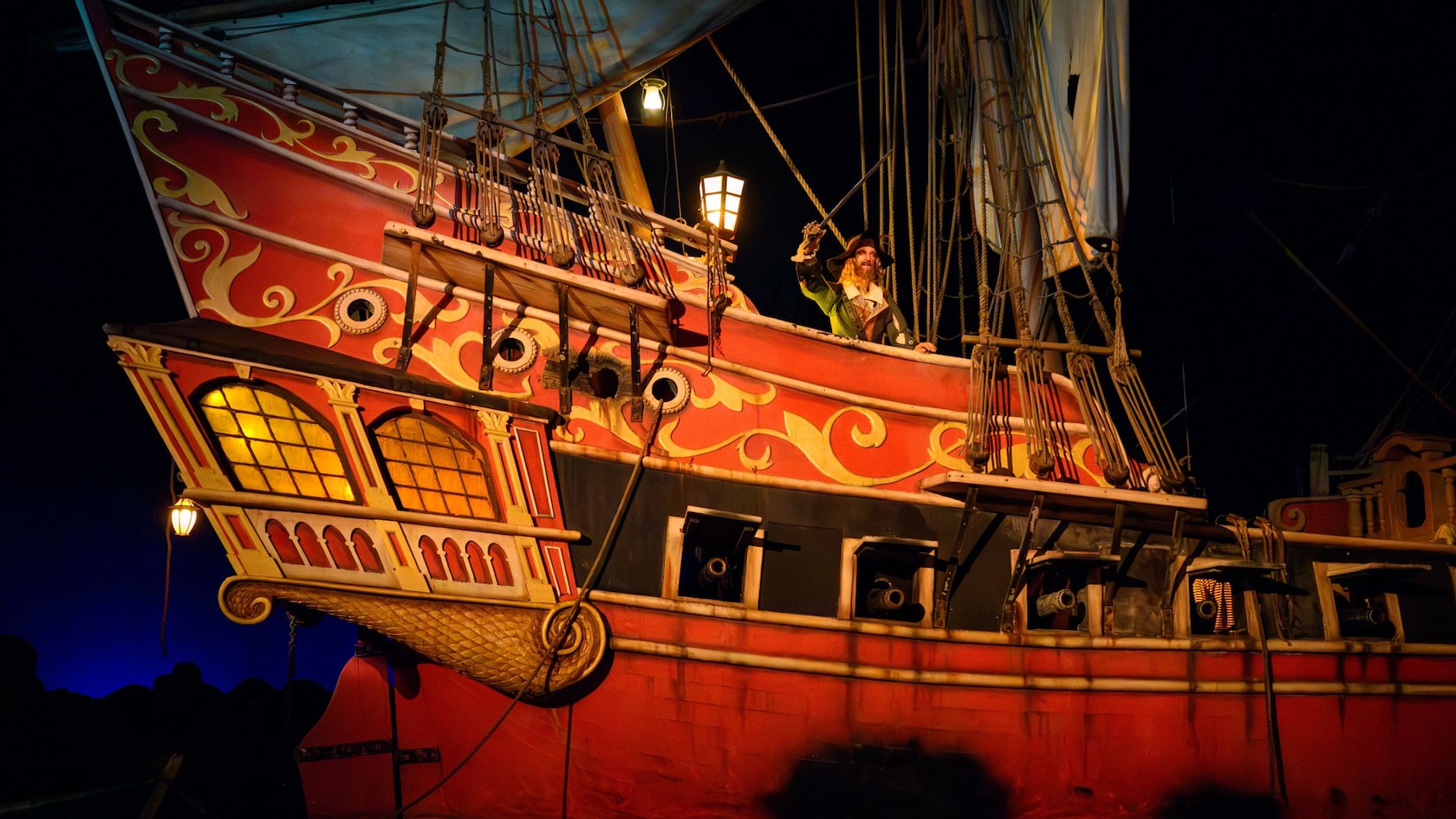 Un pirata parado en la monta de un barco en la atracción Pirates of the Caribbean