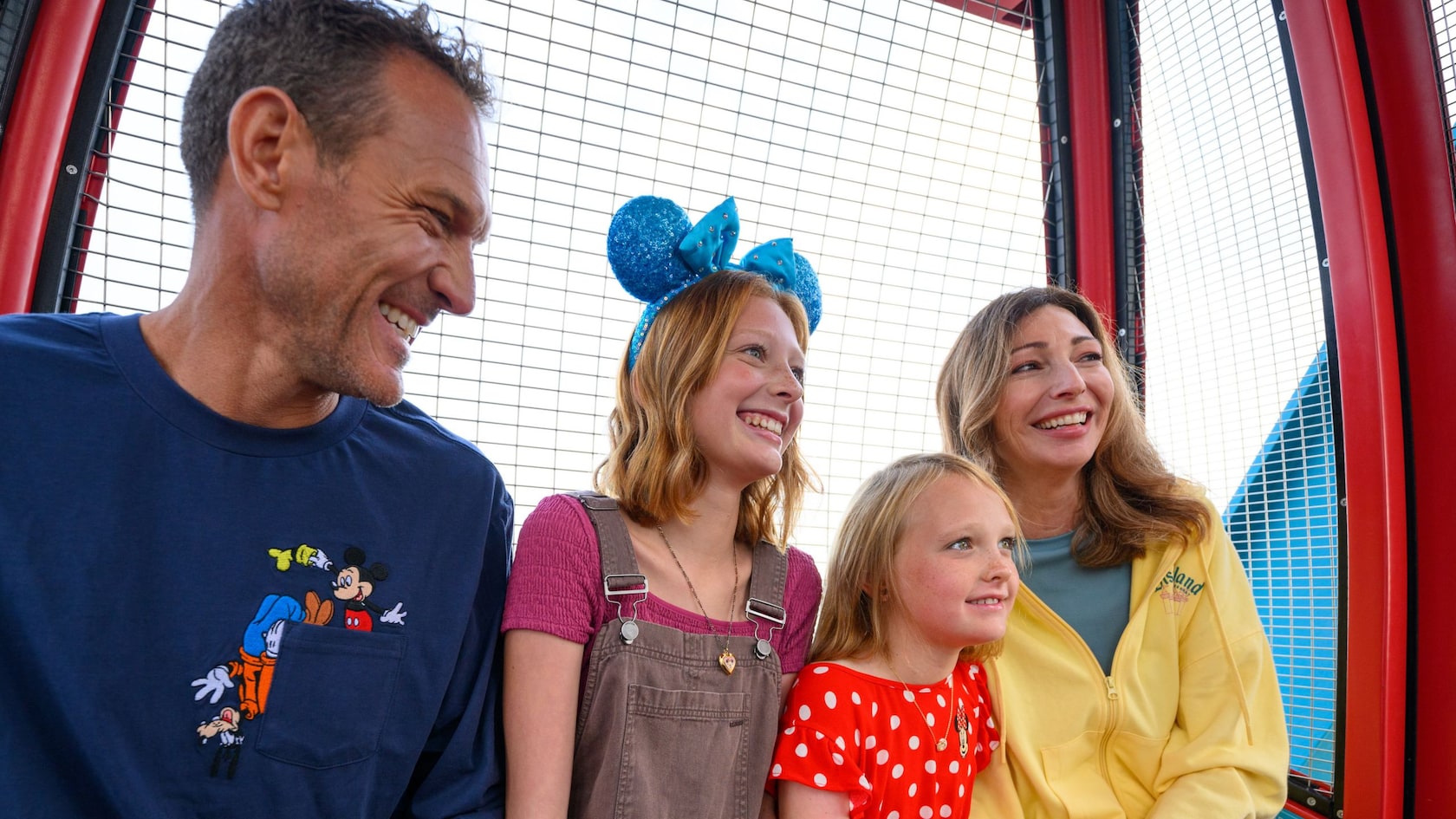 A family of 4 smiling while riding the Pixar Pal A Round Non Swinging attraction in Disney California Adventure Park