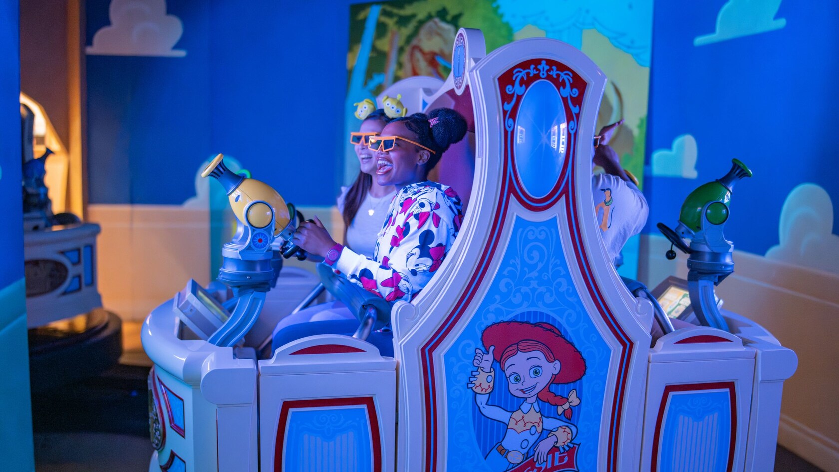2 Guests pointing their blasters at a screen in the Toy Story Midway Mania attraction at Disney California Adventure Park