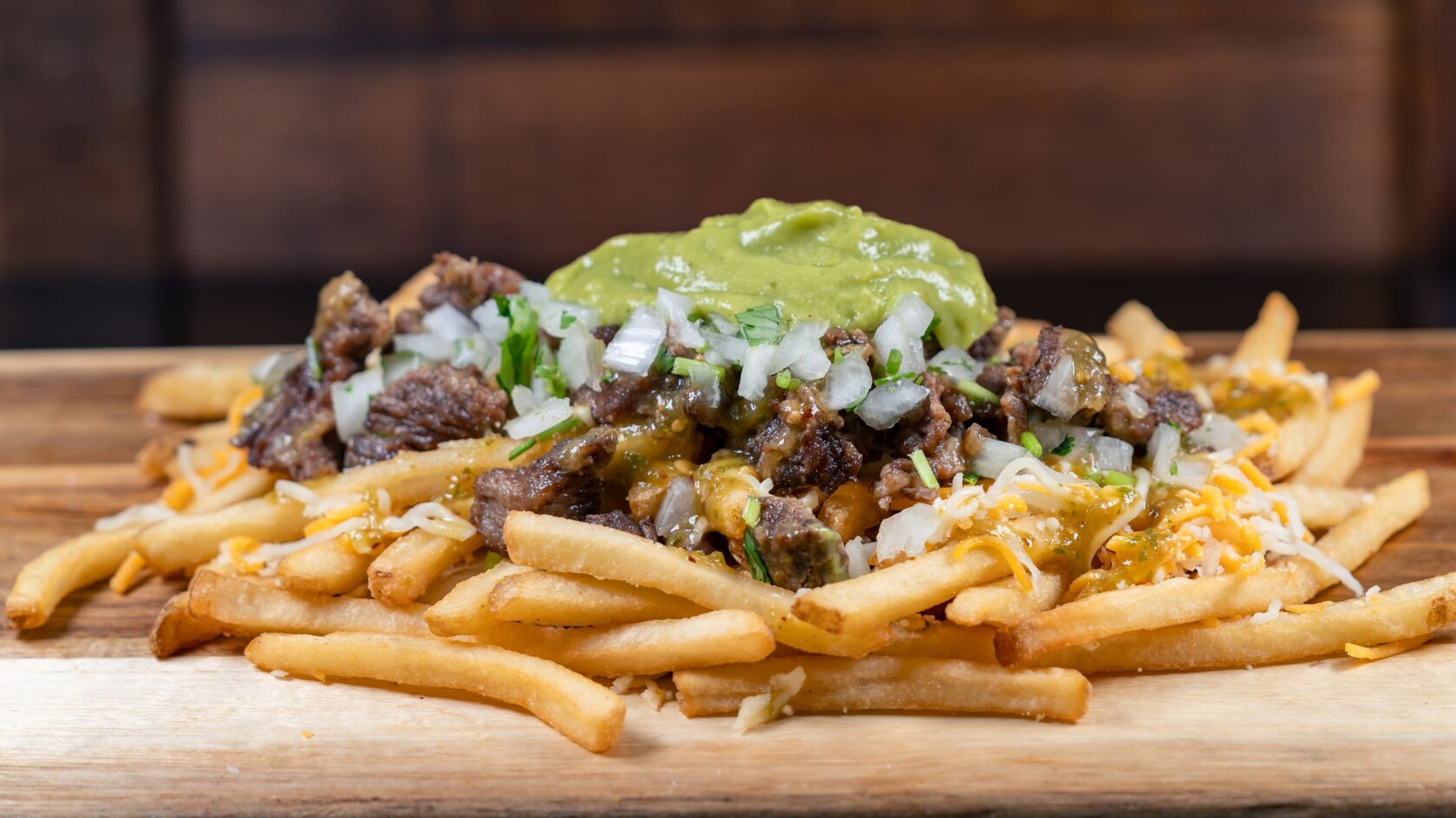 Fries topped with carne asada, cheese, cilantro, onions and guacamole