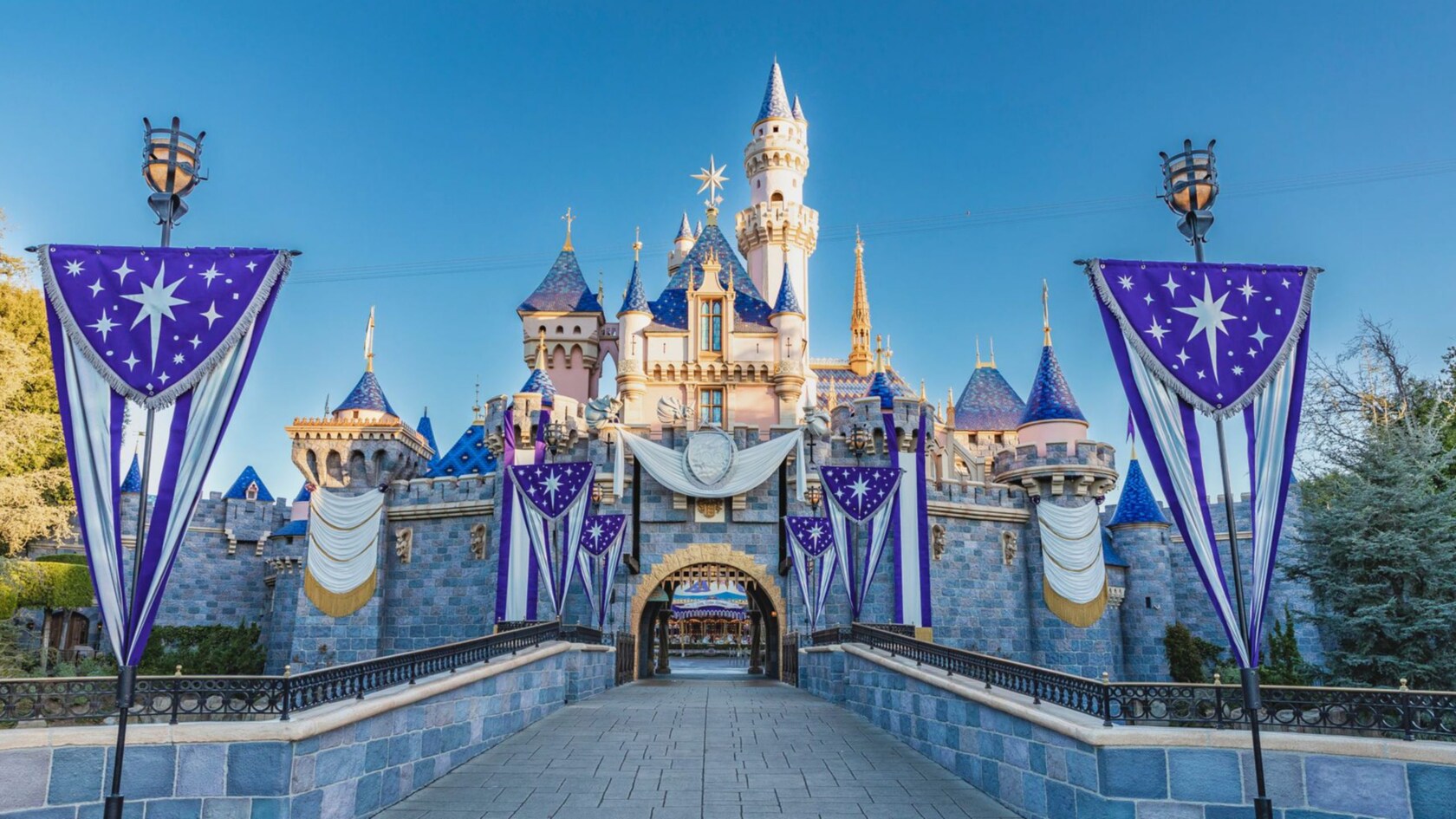 Castillo de la Bella Durmiente, adornado con elegantes banderines en honor a la Celebración Disney100 