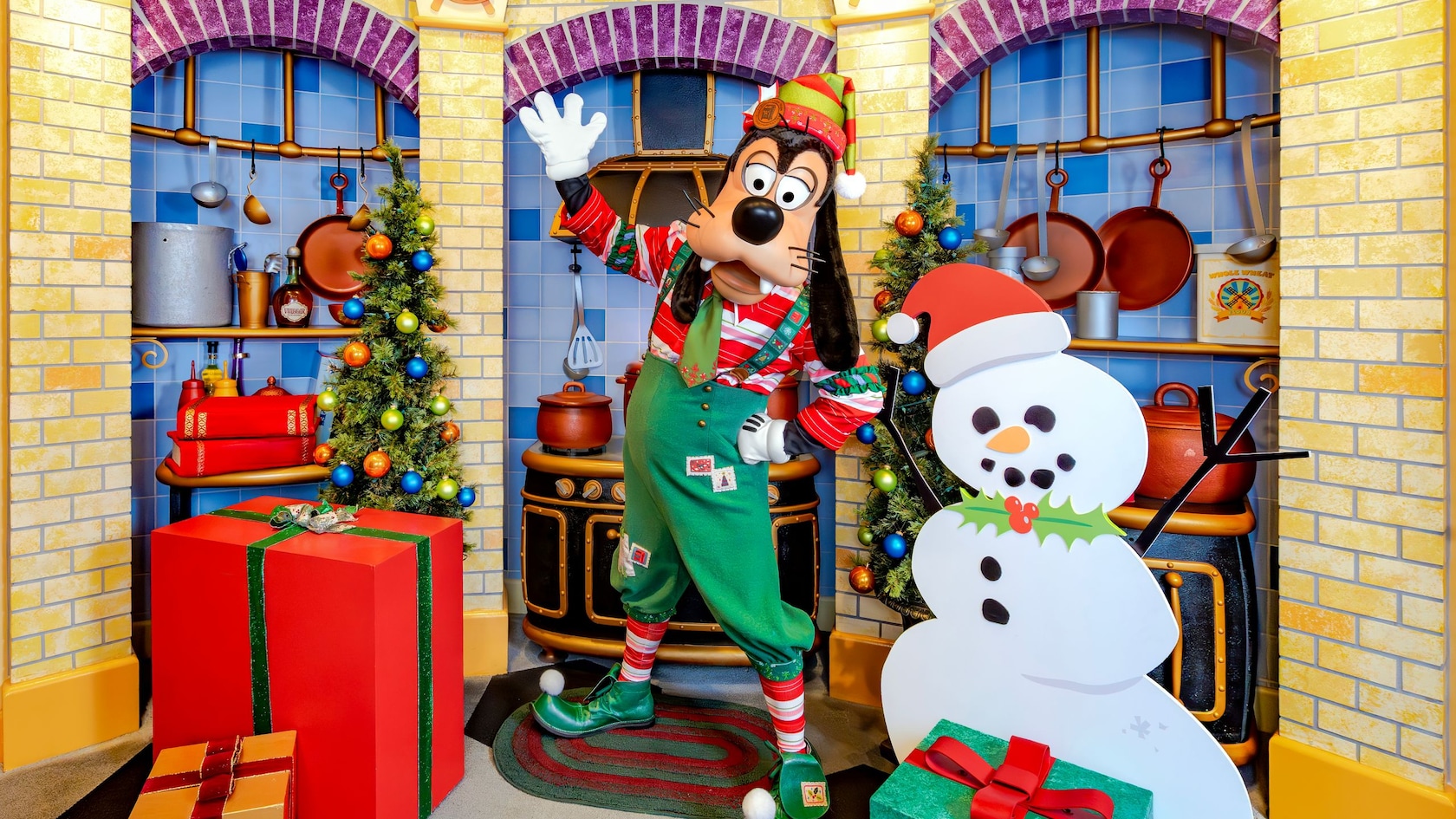 Goofy vestido con un atuendo festivo y posando para una foto en Goofy’s Kitchen, decorado para las fiestas en Disneyland Hotel